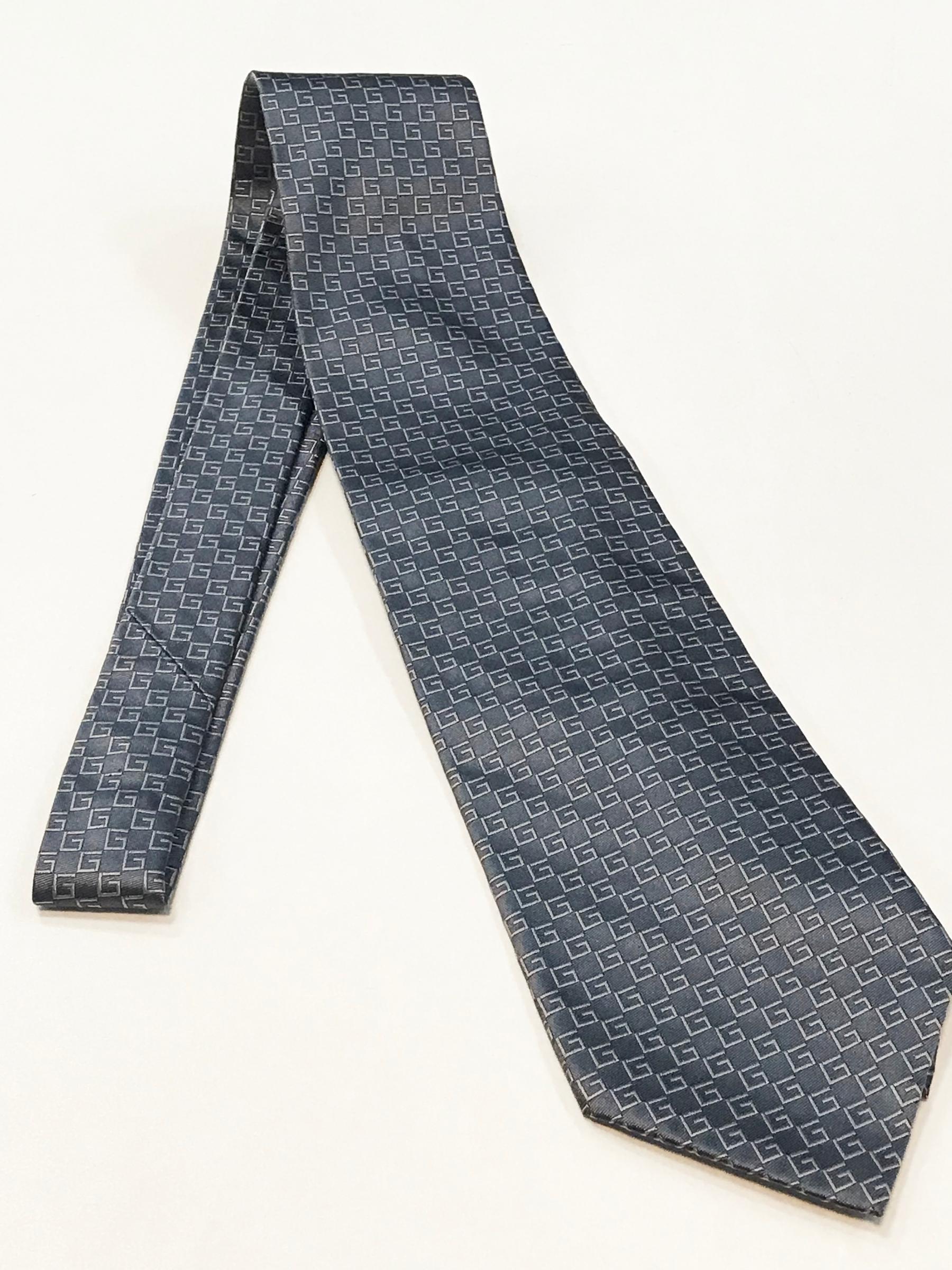 Silk ceremony silver tie by Gucci. Pattern of the textile is the Gucci logo.