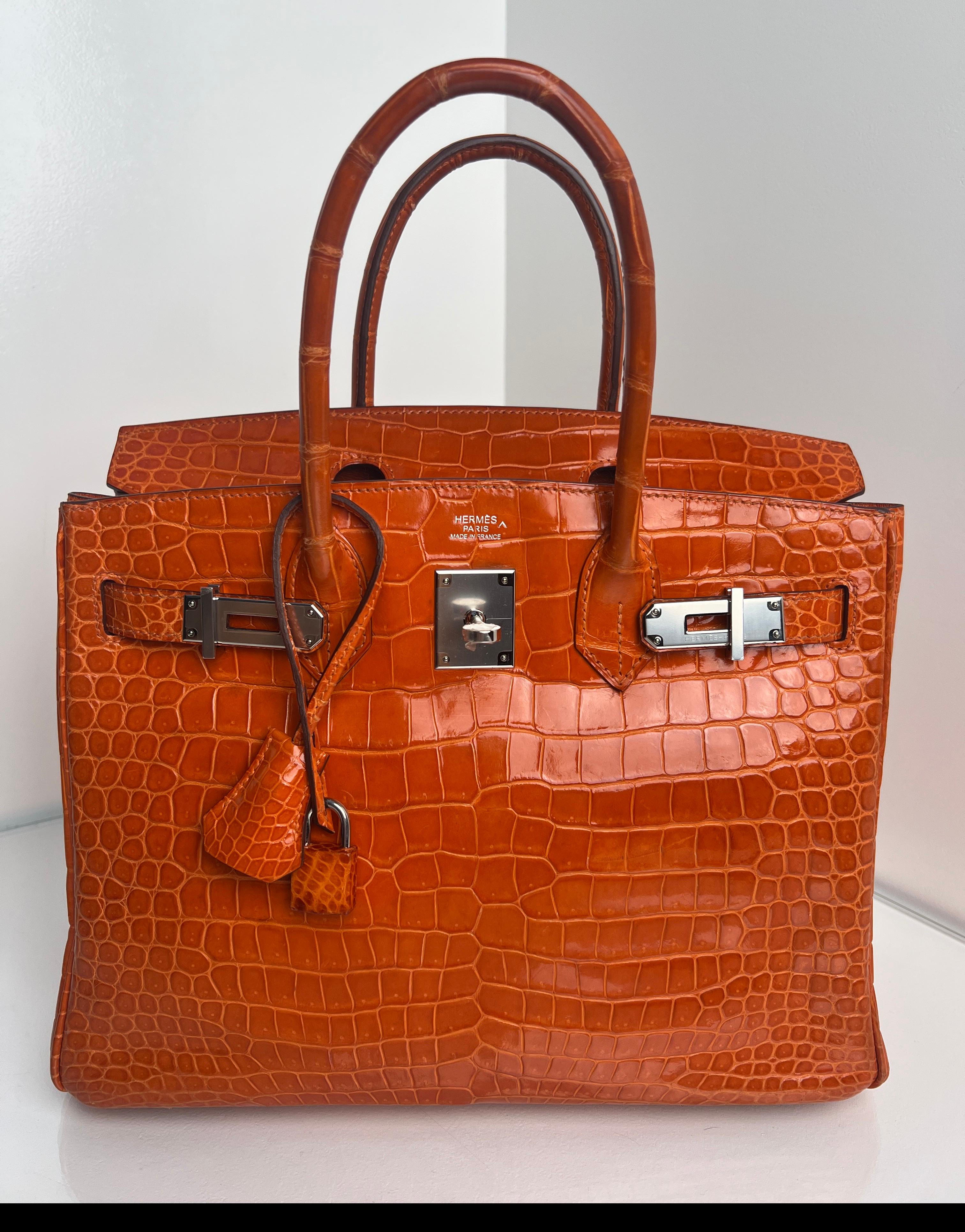 Sac Hermes Birkin 30 en crocodile orange brillant. Excellent état. Comme neuf. Le plastique est encore sur le matériel. Quincaillerie en argent palladium. Rare sac exotique en taille 30. Intérieur propre. Comprend une clochette, un cadenas, des clés