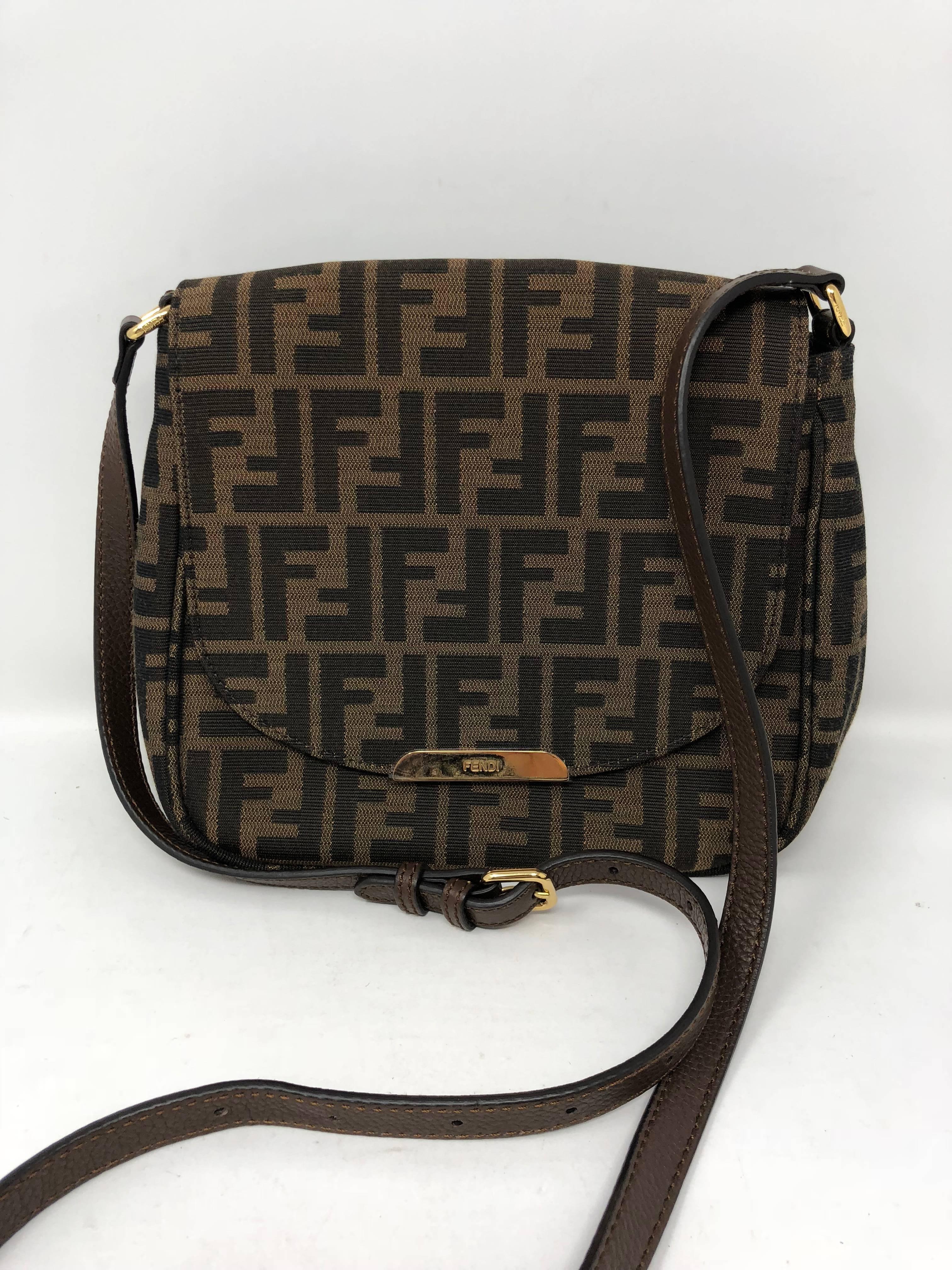 Brand new condition Fendi Crossbody bag. In traditional Fendi classic monogram print on cloth with leather handle straps. Gold hardware and accents. Zucca-print small crossbody bag with adjustable strap. Never used and plastic still on hardware. 