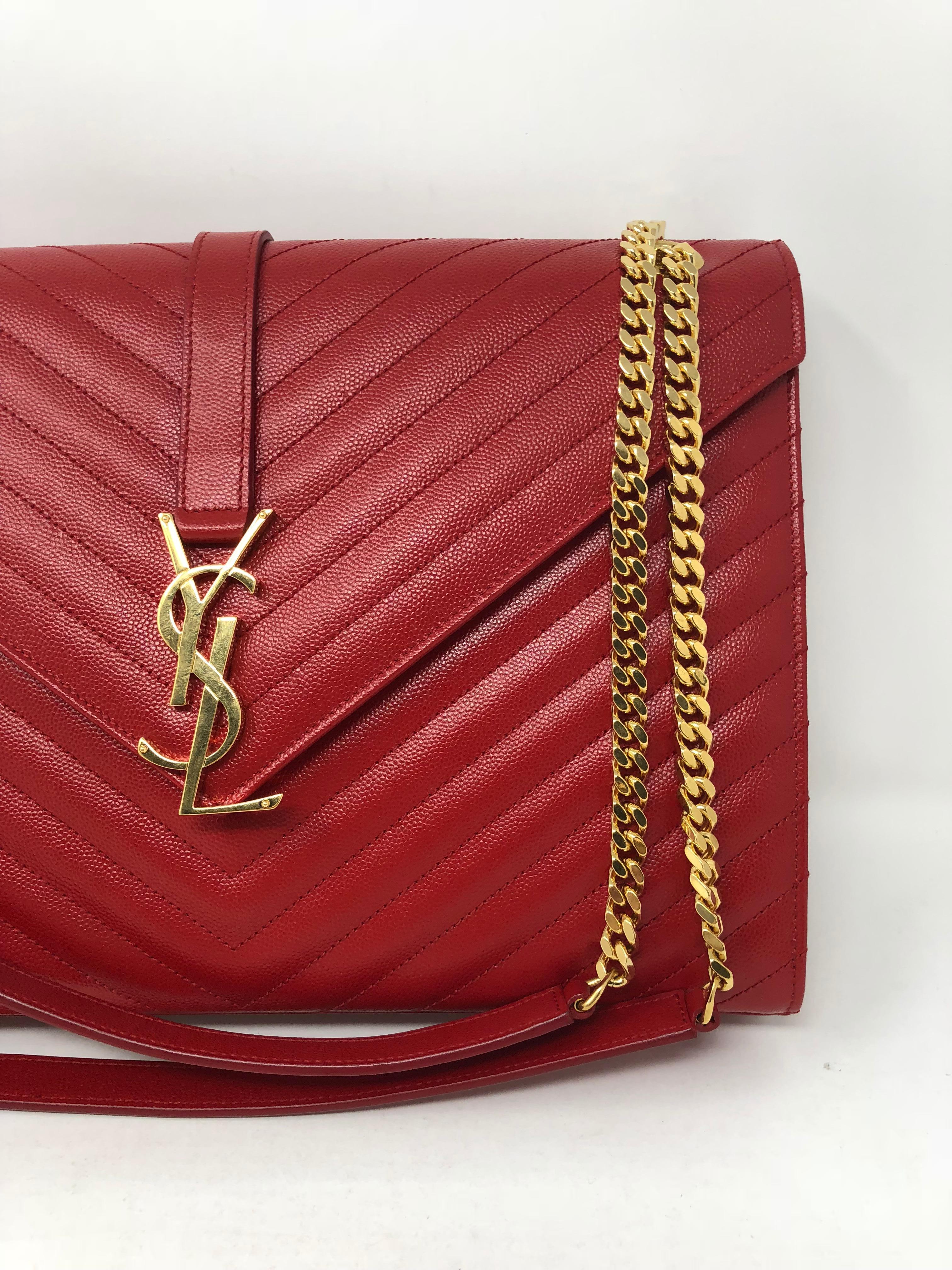 YSL Red Leather Handbag with 2 way handles in gold hardware. Large Monogram Matelasse Leather Chain Shoulder Bag. Discontinued Red Color. Brand New Condition. Never worn. Envelope Flap in Chevron leather with magnetic snap close and YSL logo.