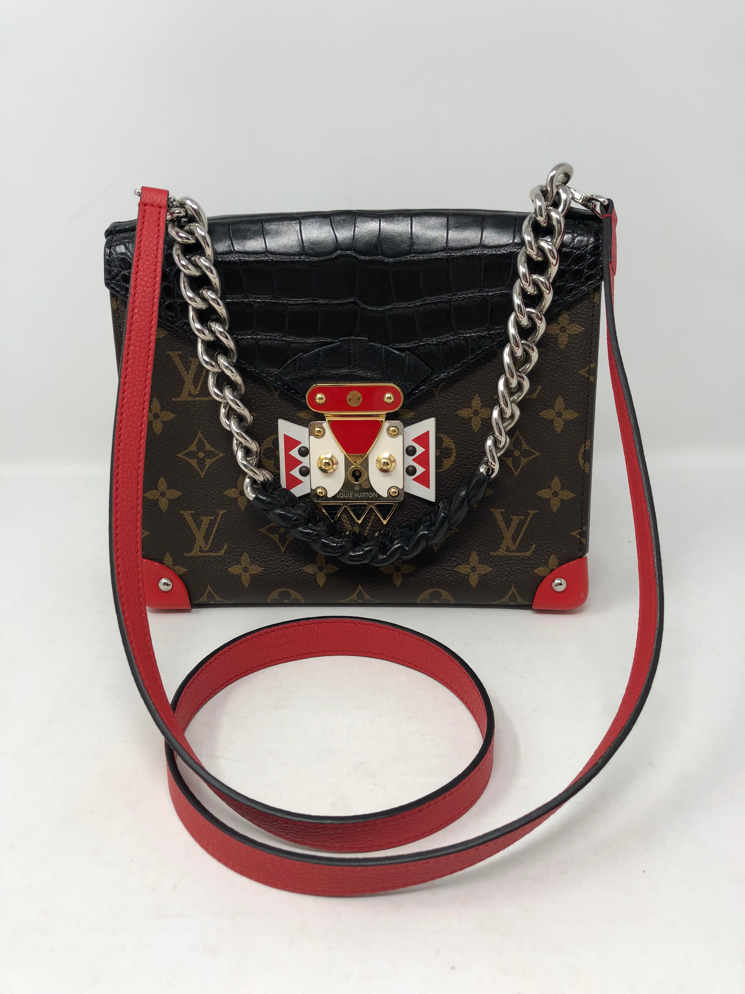 Louis Vuitton Crocodile Tribal Chain Mask Bag GM Noir Black. Very rare and unique bag by LV. Made of real crocodile and crafted of monogram toile canvas. Features a Louis Vuitton mask embellishment on the clasp. An additional new red strap was just