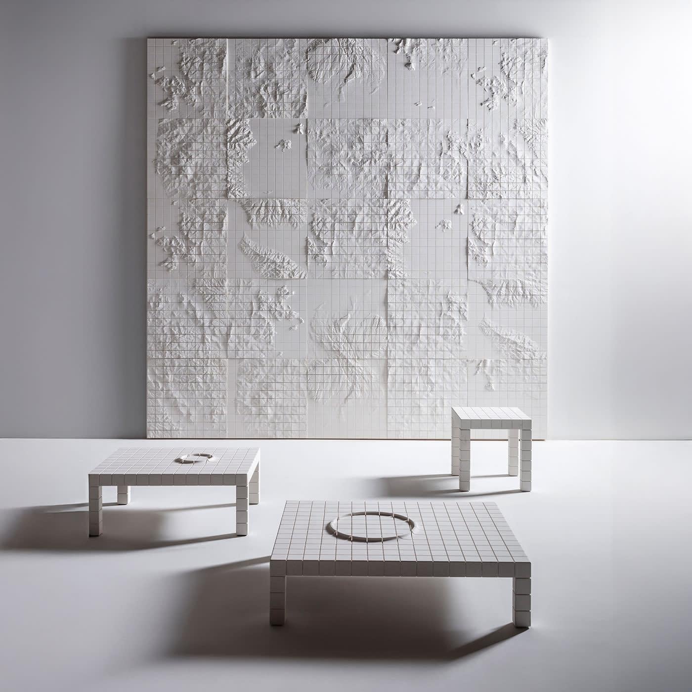 Part of the Geografia collection, the Arcipelago tables are distinguished by their precise geometric design. The internal steel structure ensures durability, while the exterior is clad in natural stone, featuring a modular grid of 6x6 cm square