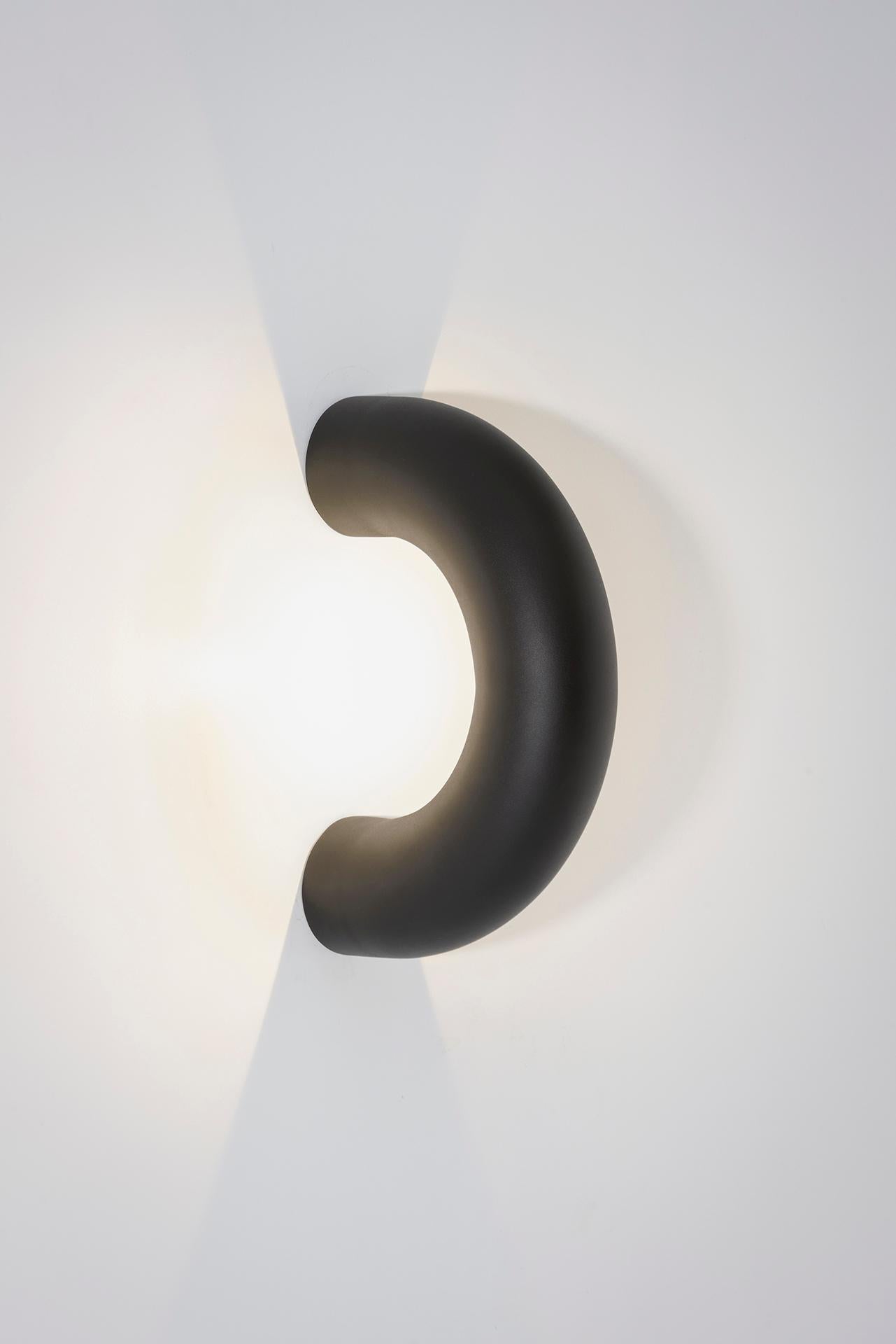 Die Arco-Lampen bestehen aus einem verlängerten Kreisausschnitt, der sich durch die Diskontinuität seiner Form auszeichnet. Die Kollektion besteht aus Lampen, die die Oberflächen, die sie berühren, zu durchdringen scheinen und sie sanft beleuchten.