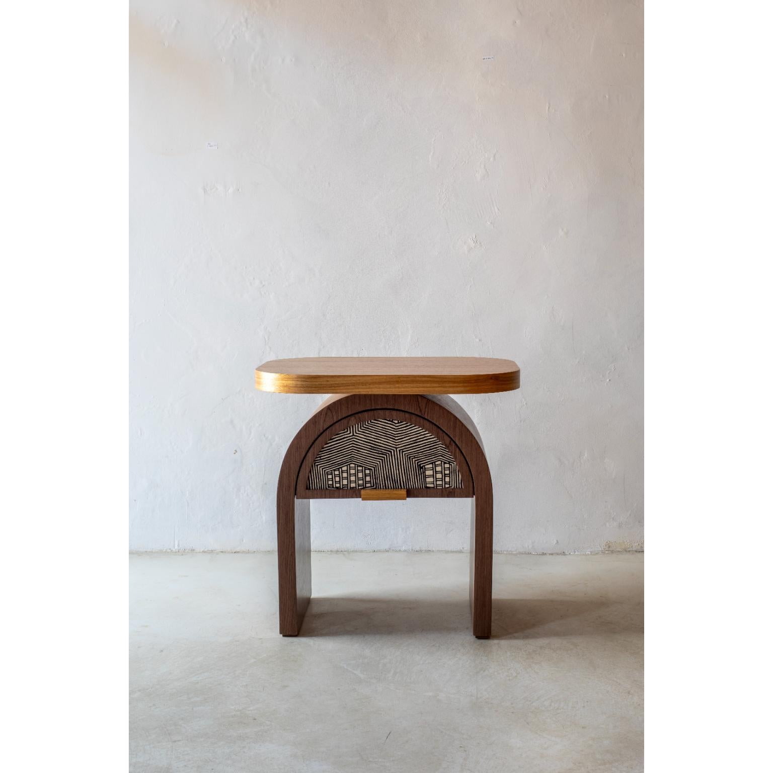 Arco Side Table by Gabriela Campos
Dimensions: D 45 x W 60 x H 60 cm.
Materials: Freijó wood with imbuia finish and hand-painted fabric.

The essence of this capsule of 4 pieces is a dialog between the Art Déco
movement and the indigenous graphics