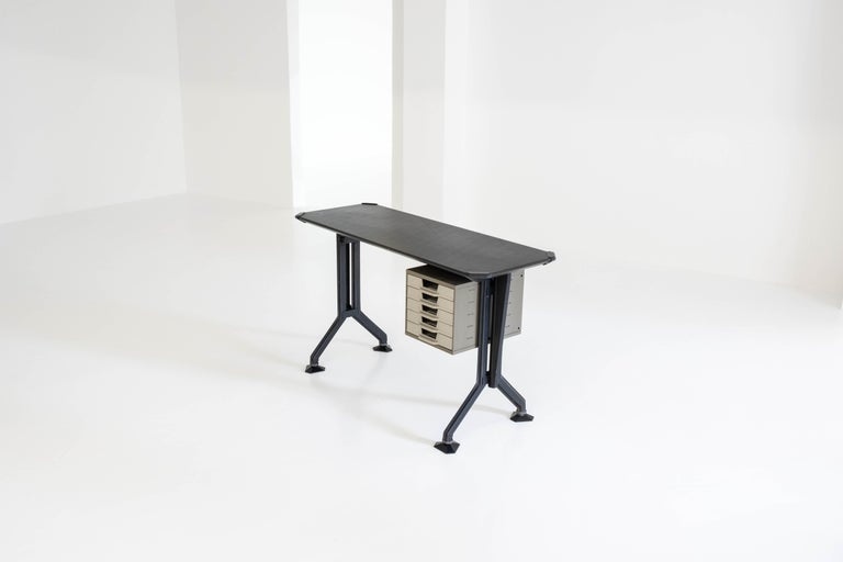 Sidedesk/desk made of metal panels on angled legs, adjustable hexagonal feet in black and a chest of five drawers on rails in light gray / beige plastic, which is in a good vintage condition. the tabletop is in black vinyl which shows some lovely