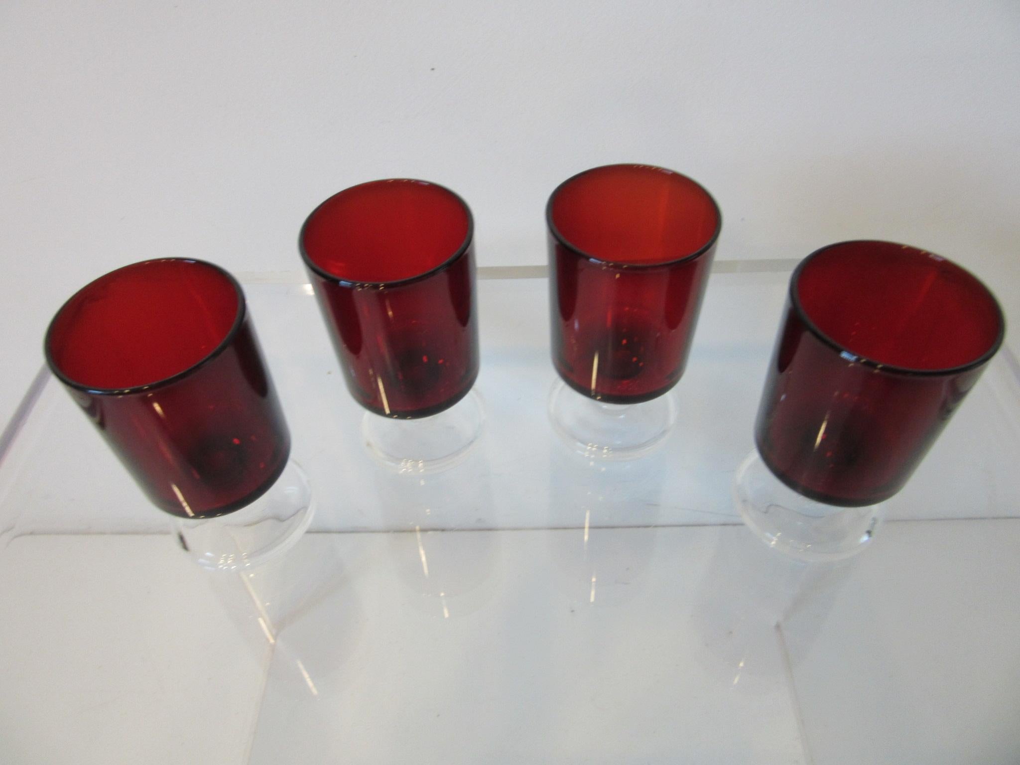 Un ensemble de quatre verres à liqueur à pied transparent et de couleur rouge rubis profond de la marque Arcoroc, parfaits pour compléter l'ensemble de verres à liqueur ou pour votre bar. Estampillé made in France au bas des verres et conçu par J.G