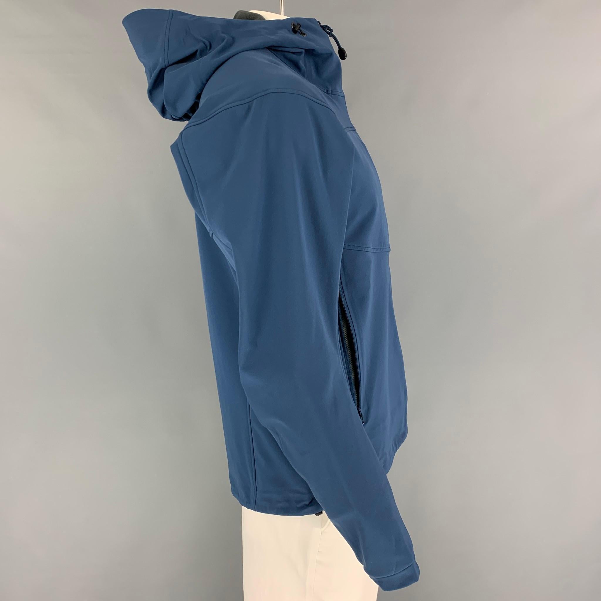 ARCTERYX jacket comes in a blue nylon blend with a grey fleece liner featuring a hooded style, front pockets, sleeve pocket, and a full zip up closure. 

Very Good Pre-Owned Condition.
Marked: L
Original Retail Price:
