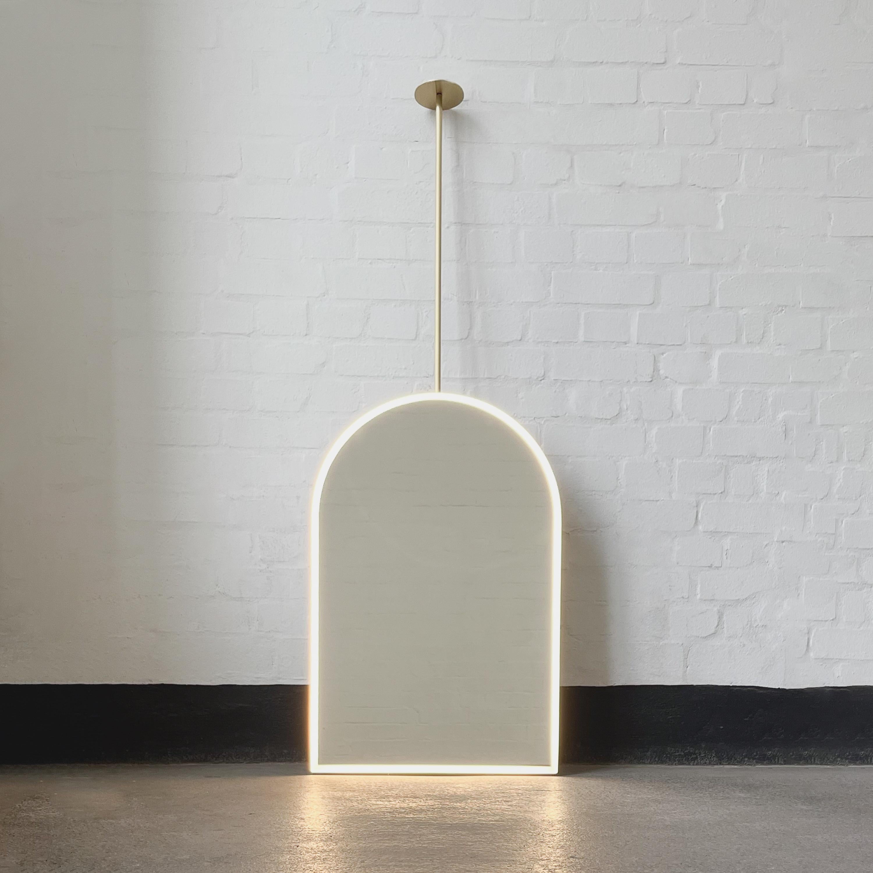 Modern ceiling suspended Arcus™ arched mirror with a minimalist brushed brass frame and front illumination. Designed and handcrafted in London, UK. This mirror is fully customisable to suit the specific requirements of each interior.

Mirror