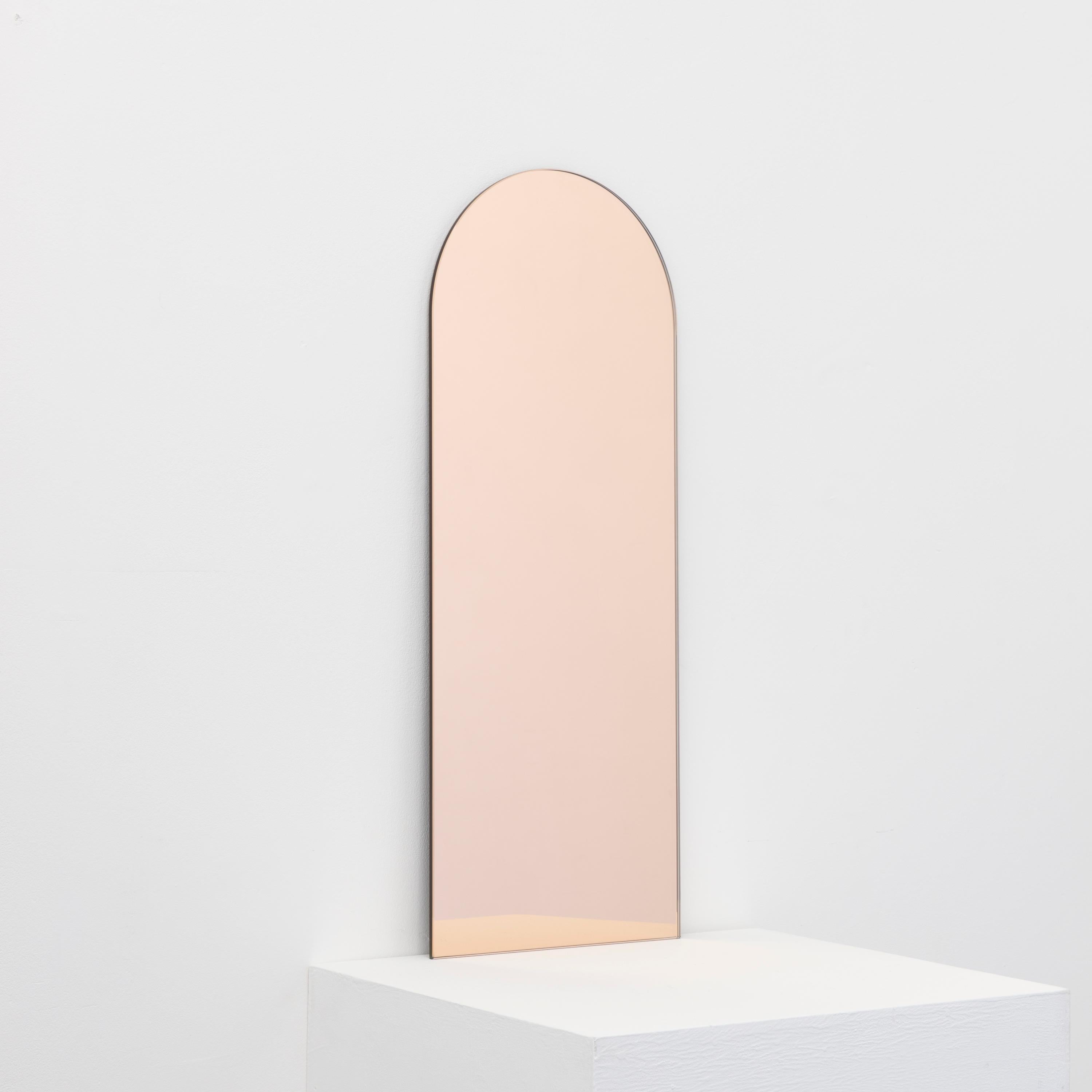Minimalist arch shaped frameless rose gold tinted mirror with a floating effect. Quality design that ensures the mirror sits perfectly parallel to the wall. Designed and made in London, UK.

Fitted with professional plates not visible once installed