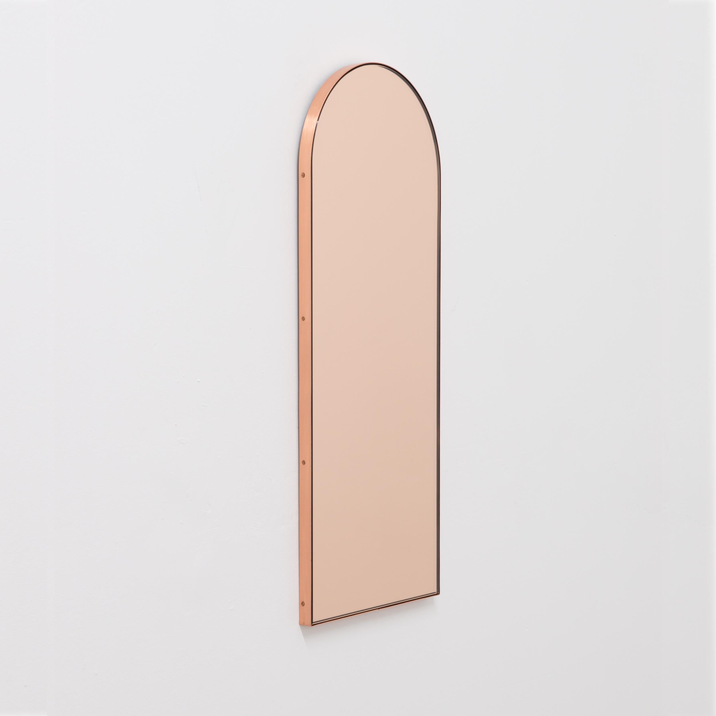 Miroir contemporain en forme d'arche en or rose / pêche avec un cadre élégant en cuivre massif brossé. Conçu et fabriqué à la main à Londres, au Royaume-Uni.

Les miroirs de taille moyenne, grande et extra-large (37cm x 56cm, 46cm x 71cm et 48cm x