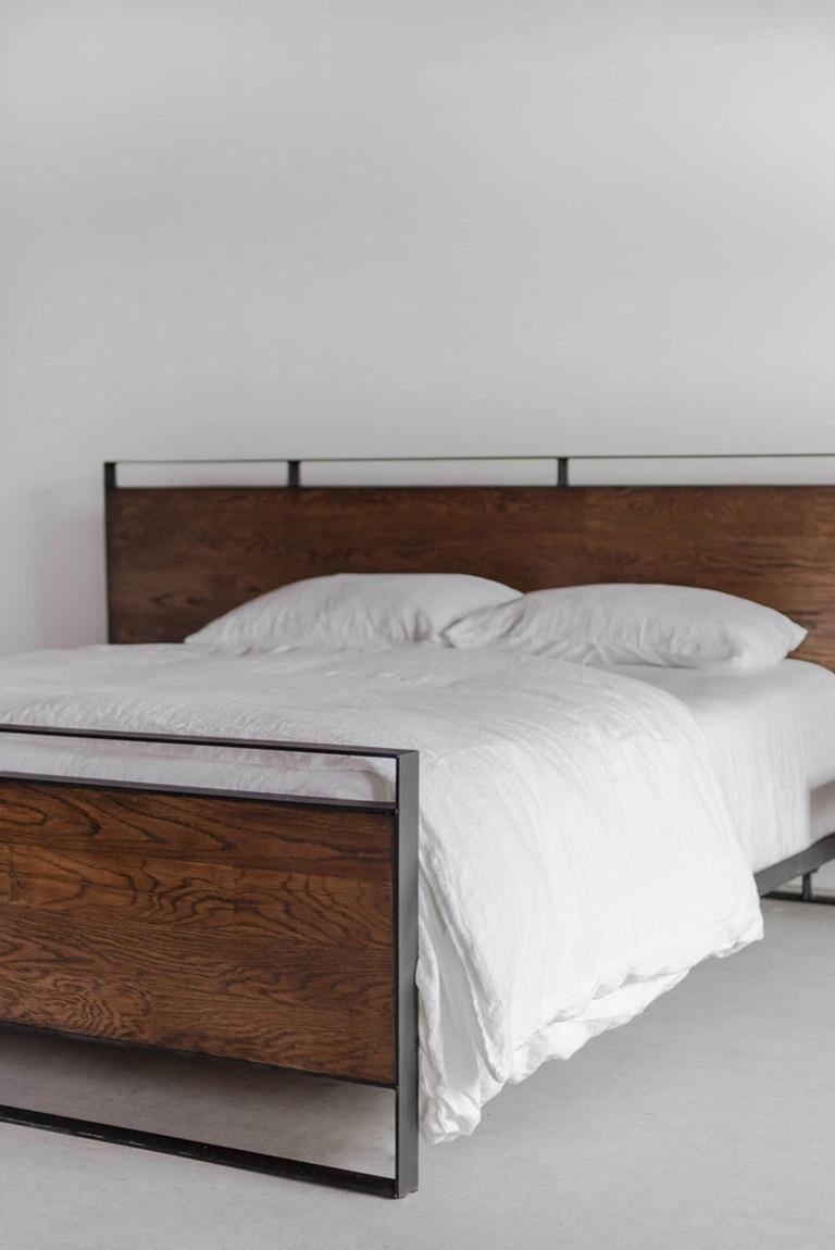 The Arden Bed combines modern design and natural materials, featuring warm medium-toned oak boards framed and highlighted by a matte black trim. Despite its large scale, the headboard has a thin profile and look that adds to the bed's contemporary