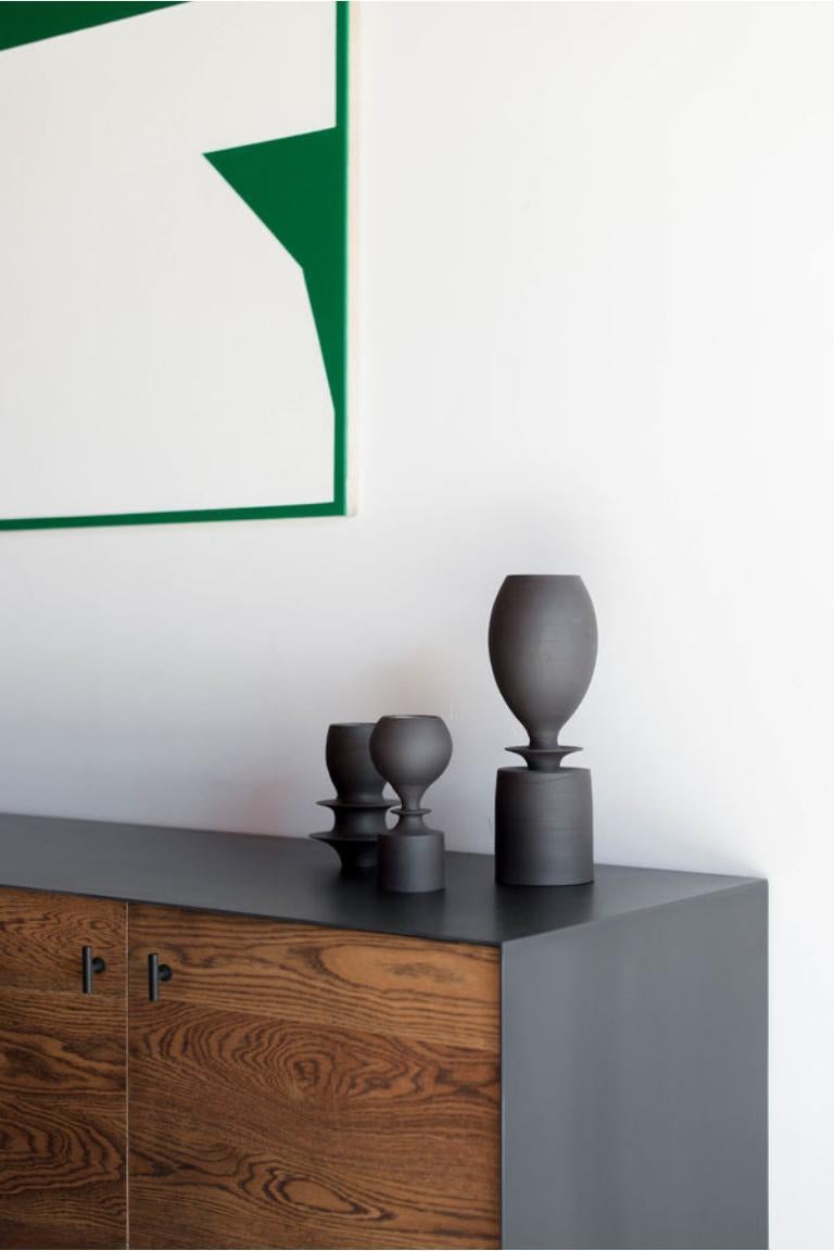 Esta Credenza se fabrica a medida en Los Ángeles. La carcasa de acero industrial se recorta a medida y se fija a un sustrato. La madera se corta a medida y se une a las caras de la puerta. Cuatro puertas con tiradores negro mate y bisagras de cierre