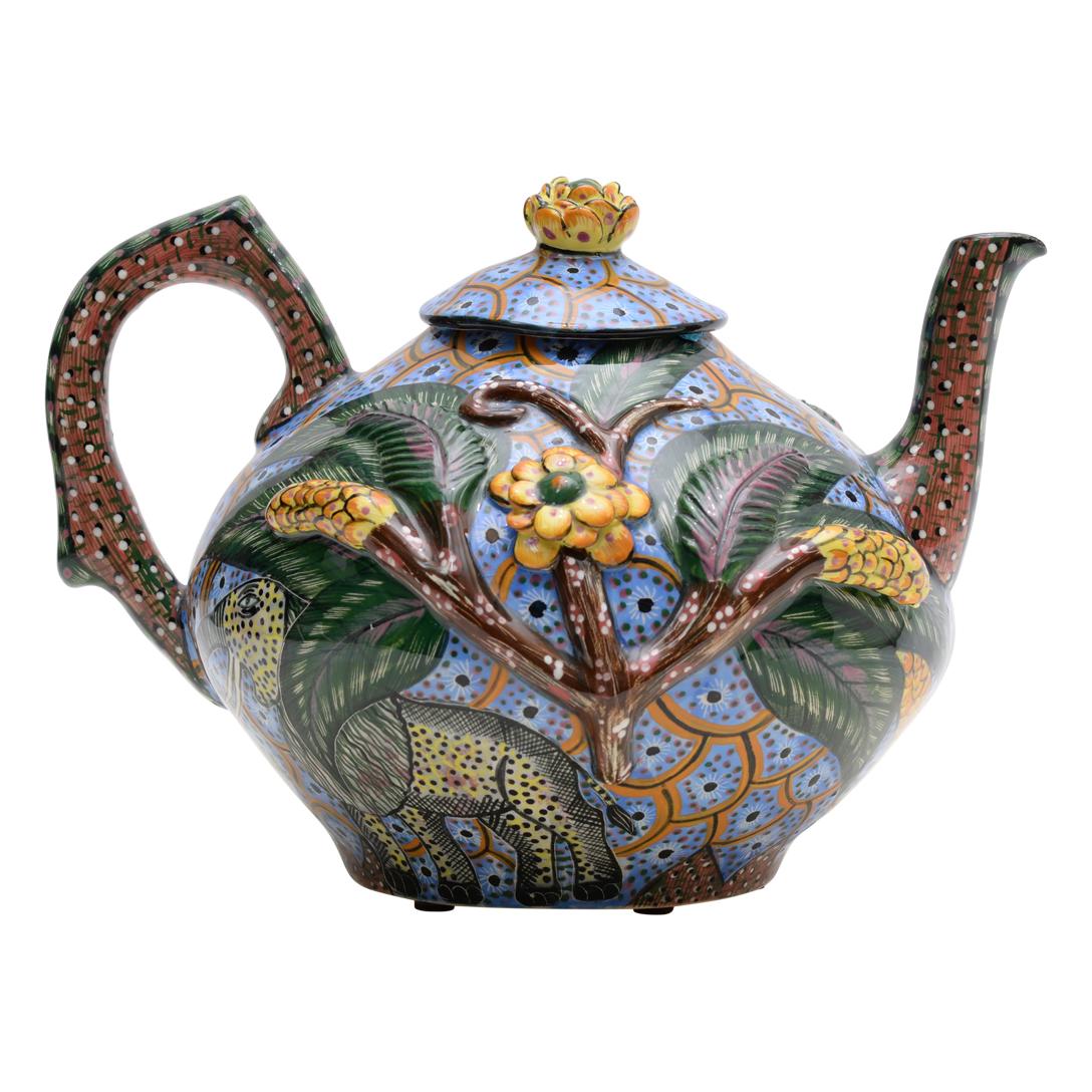 In the heart of South Africa, Ardmore Ceramics unveils a marvel: the Elephant Teapot. Crafted by Agnes Ndlovu Ntshalintshali and painted by Ottilia Nxumalo, it stands 7 inches tall, with a length and width of 10 and 9 inches, respectively. Adorned