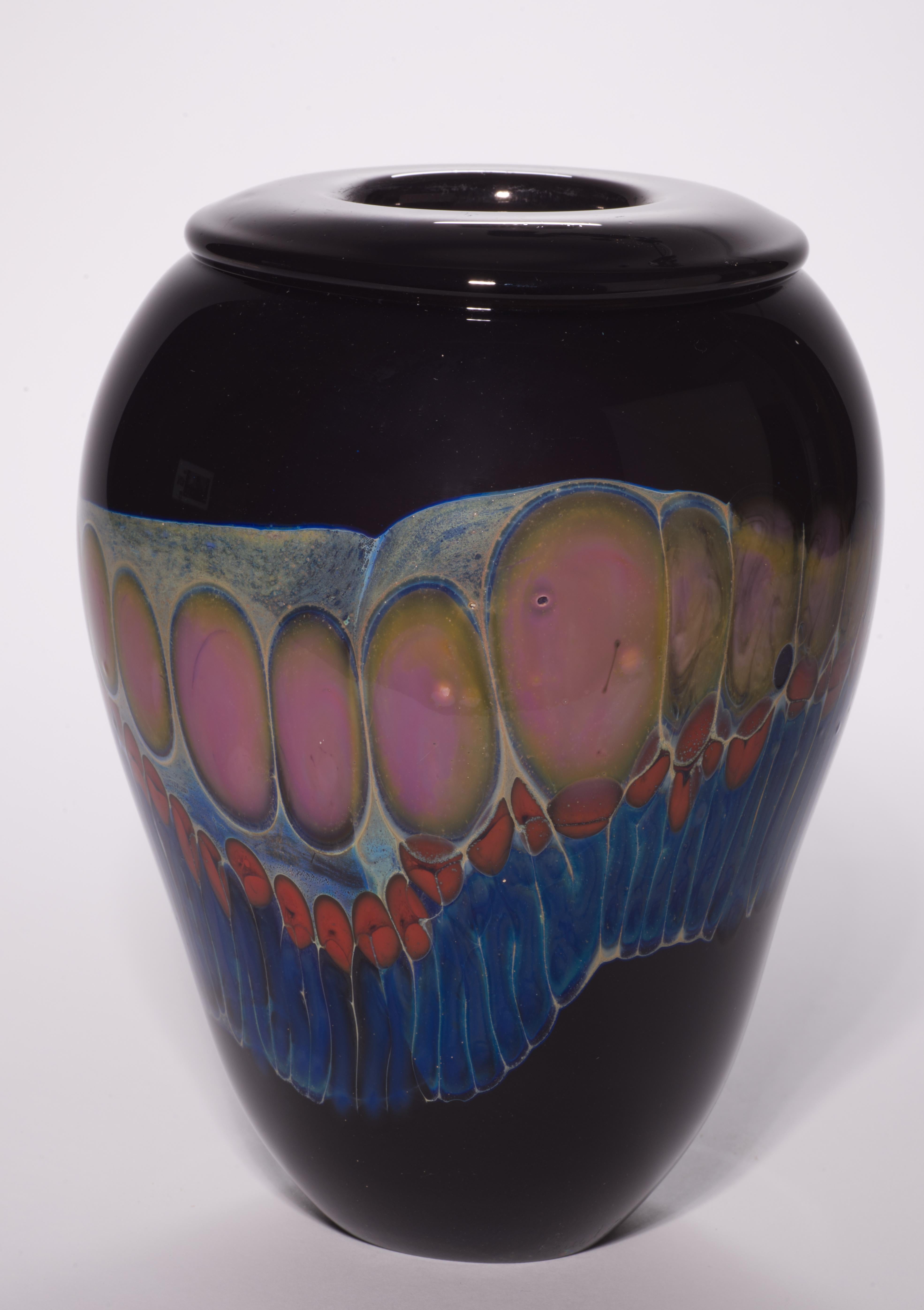  Il vaso scultoreo e colorato è decorato con un'ampia fascia di schizzi policromi e fili di vetro su uno sfondo di vetro nero quasi completamente opaco; la fascia scorre liberamente in modo asimmetrico lungo la superficie del vaso, incastonando e