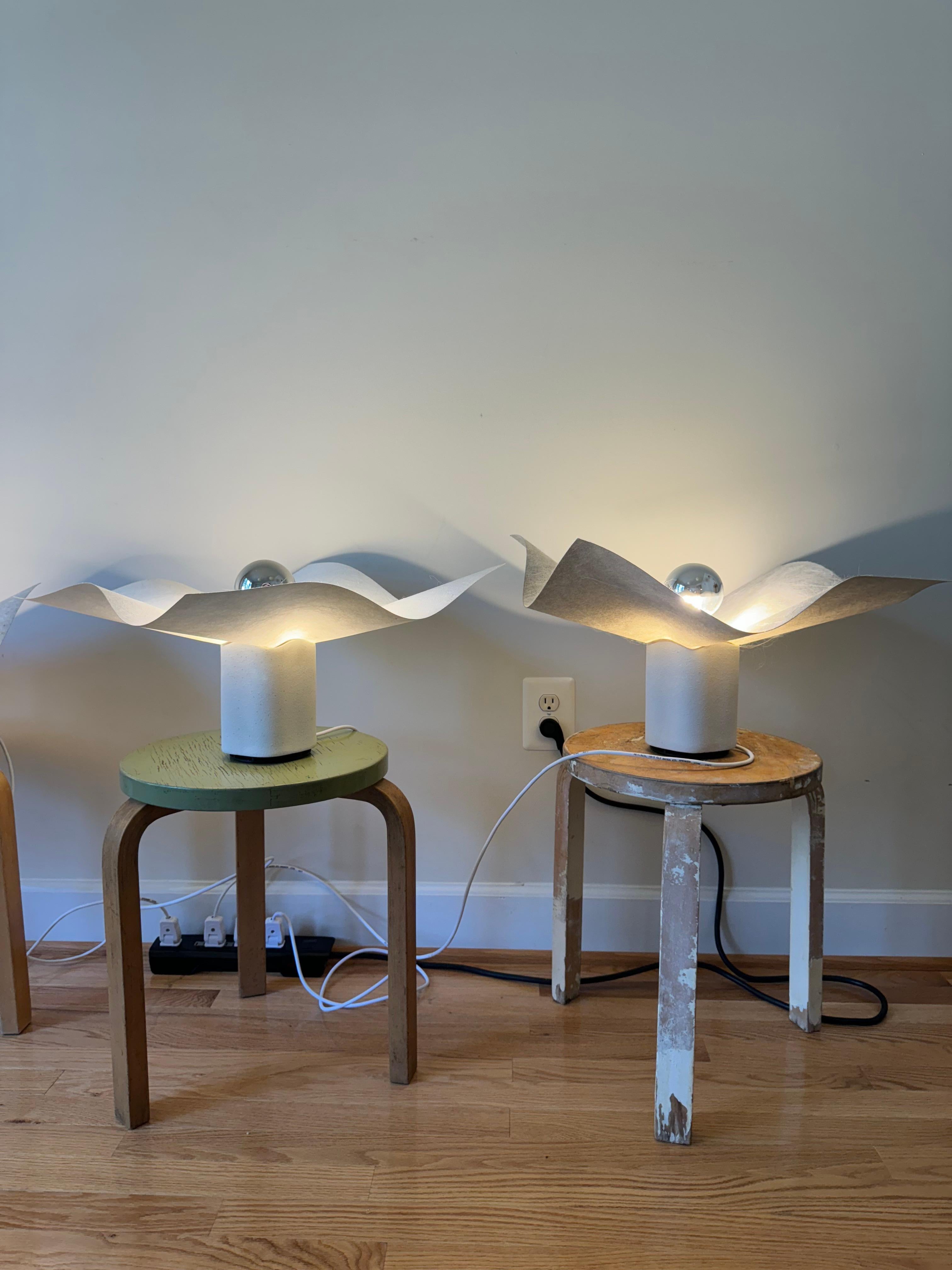 The Area 50 table lamp is part of a series of table, floor, wall and ceiling lamps designed by Mario Bellini in 1974 for Artemide. 
Bellini says he designed the lamps in relation to the immaterial nature of light, so rather than creating an object,