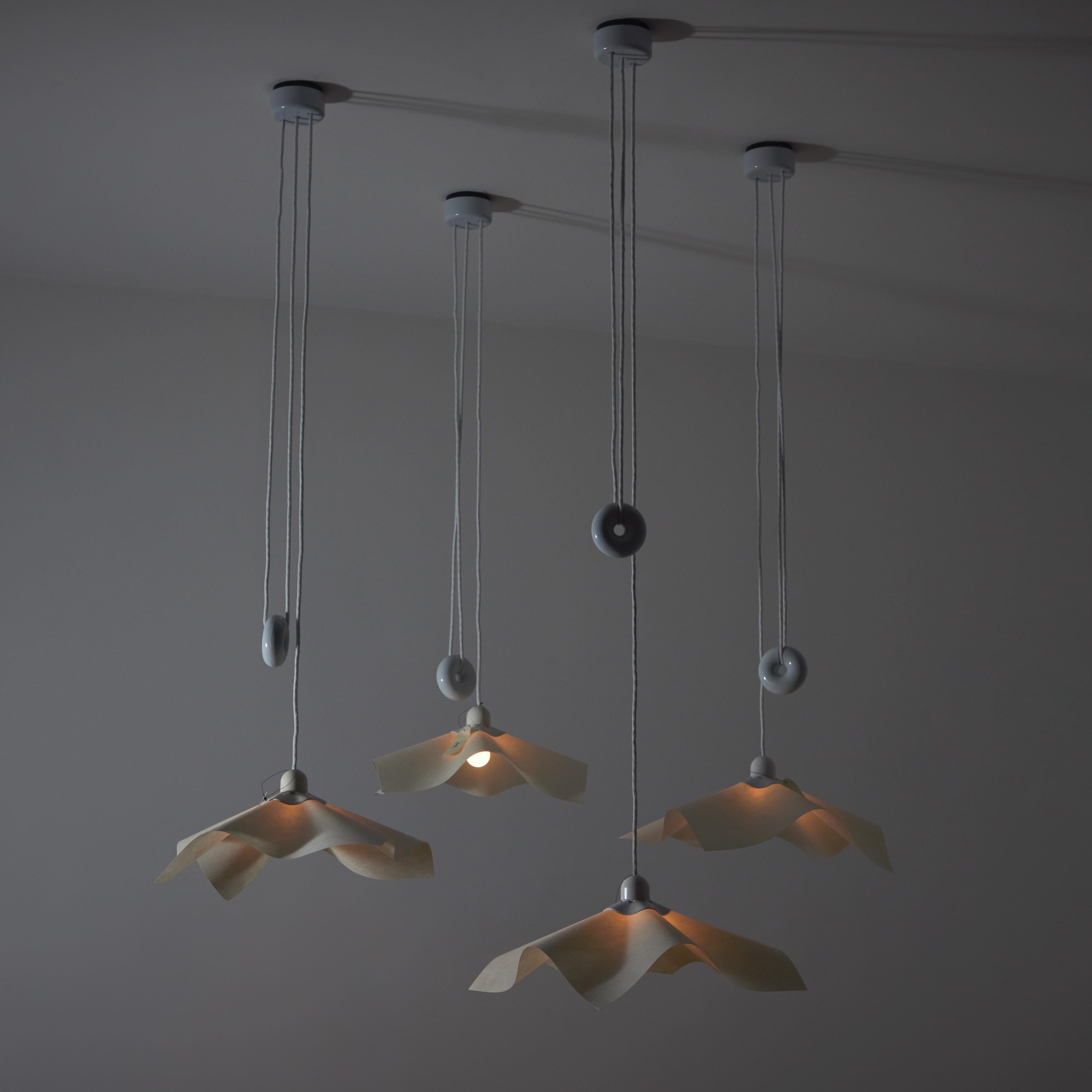 'Area 50' Pendants by Mario Bellini for Artemide. Designed and manufactured in Italy, 1976. Iconic model from Bellini consist of a counter donut weight allowing for variable adjustments to the height. The shade comprises of molded parchment paper.