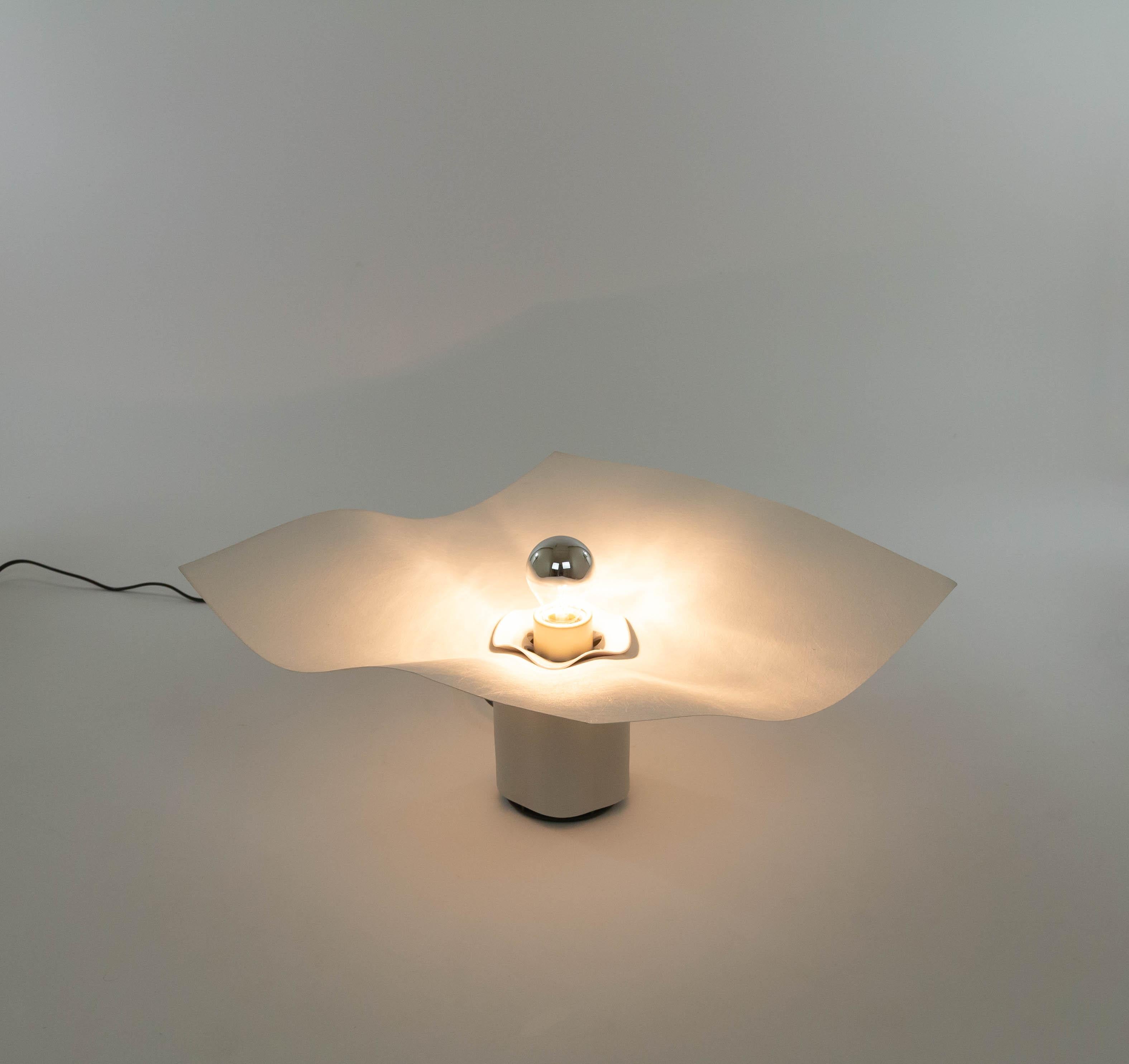 Area 50 table lamp, designed by Mario Bellini and manufactured by Artemide in the 1970s.

The lamp consists of a white matt porcelain base (18 cm / 7 inch high) and a cream coloured diffuser in synthetic textile. A plastic part together with the