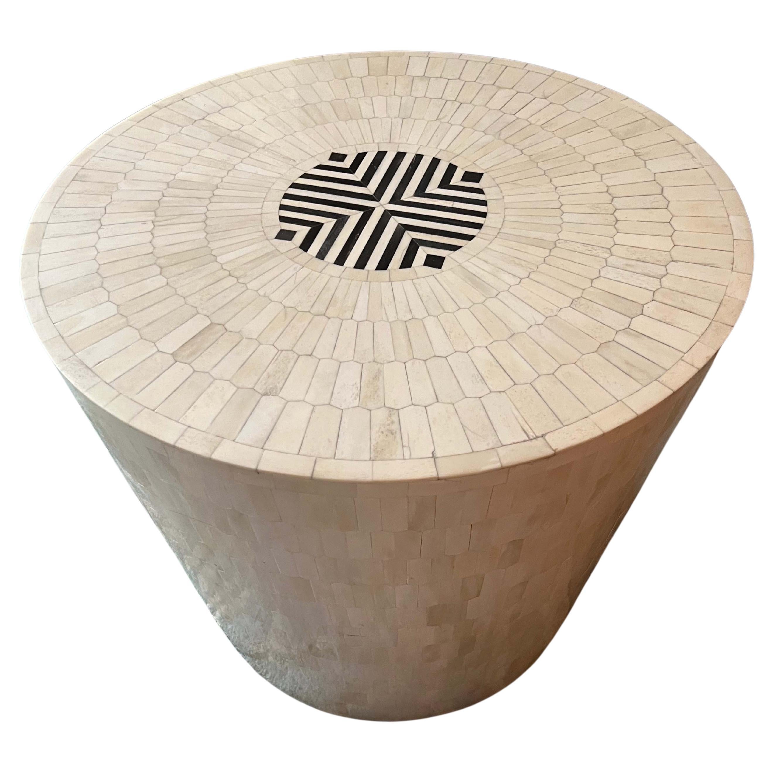 Der Arena Hocker oder Beistelltisch ist aus Holz gefertigt und mit Hunderten von nachhaltig beschafften, handgeschnitzten sechseckigen Knochenspänen mosaikartig verziert, die ein subtiles Ton-in-Ton-Muster ergeben. Die Oberseite ist mit einer