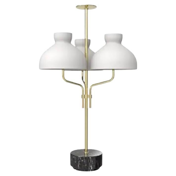 A lamp born as a natural evolution of its sister with a single diffuser. Its body is made of wisely woven pipes, curved and grafted together to form a brass jewel. A rational marble base typical of the designer and a knob at the top to balance this