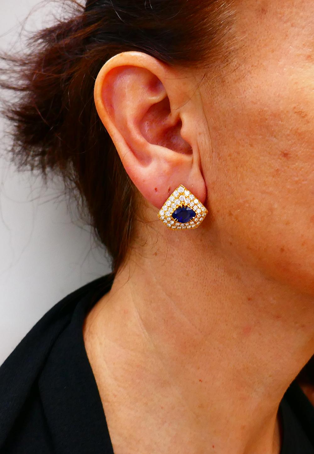 A pair of vintage French 18k gold earrings, featuring sapphire and diamond.
The earrings are made in an irregular pentagon shape. The diamonds are four-prong set in two rows around the perimeter. The marquise shaped sapphires are staged in the