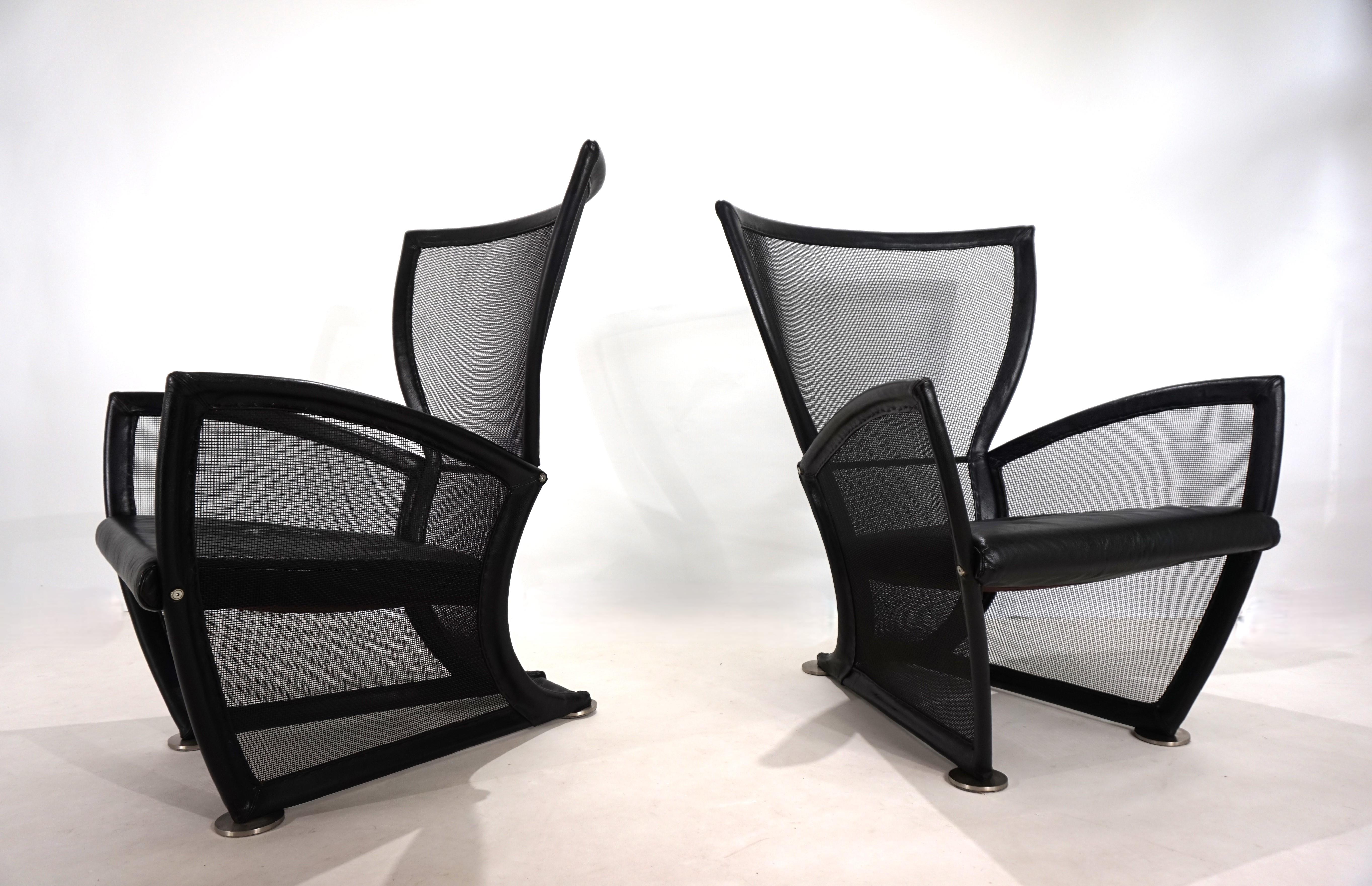Este sillón Prive con malla metálica negra y tapicería de cuero negro está en excelente estado. Ambos sillones presentan una muy buena impresión, con mínimos signos de desgaste. La malla metálica recubierta de plástico negro no presenta signos de