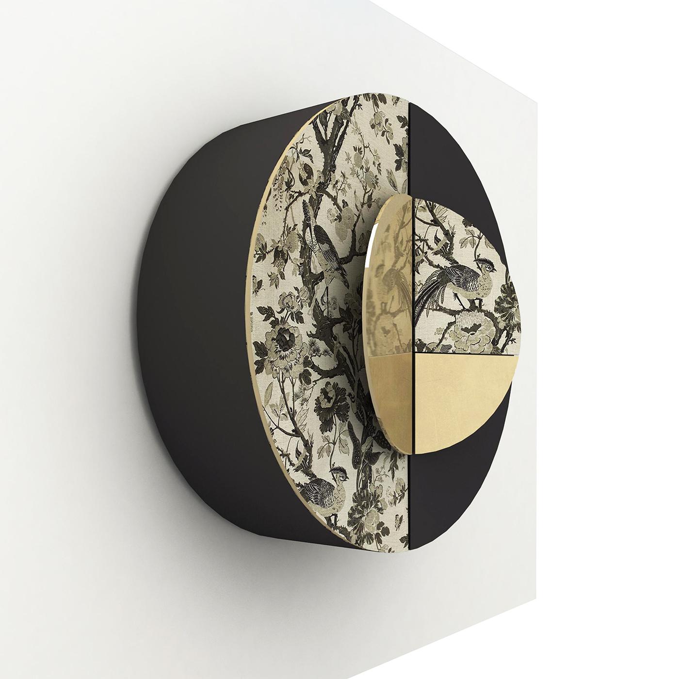 D'un design élégant et contemporain, cette armoire murale présente une silhouette ronde fabriquée à la main dans des matériaux raffinés. La structure en bois poli noir est partiellement tapissée d'un tissu oriental raffiné réalisé à la main sur des