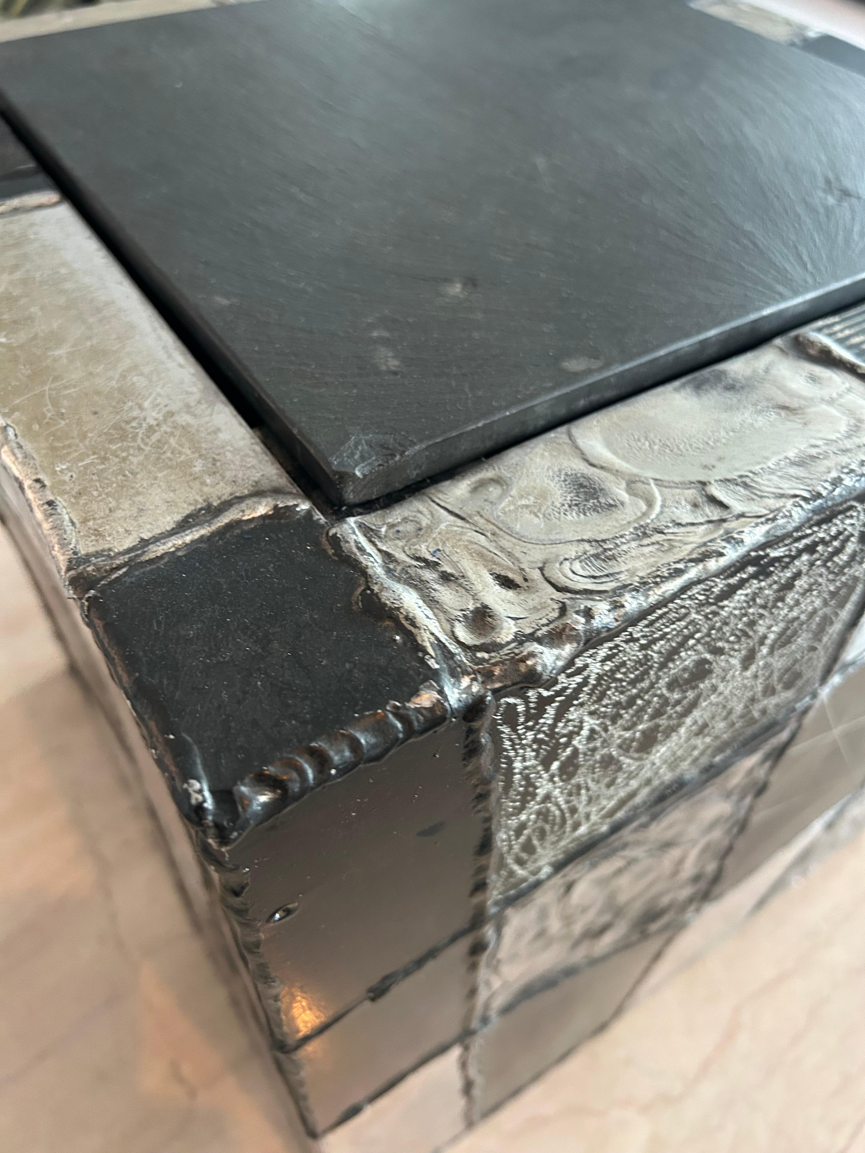 Paul Evans model PE – 37 cube side table. Welded aluminum construction with etched patterns on oxidized and painted panels.. with an inset black slate top. Manufactured by Paul Evans studio for directional. C 1969. This table is in showroom
