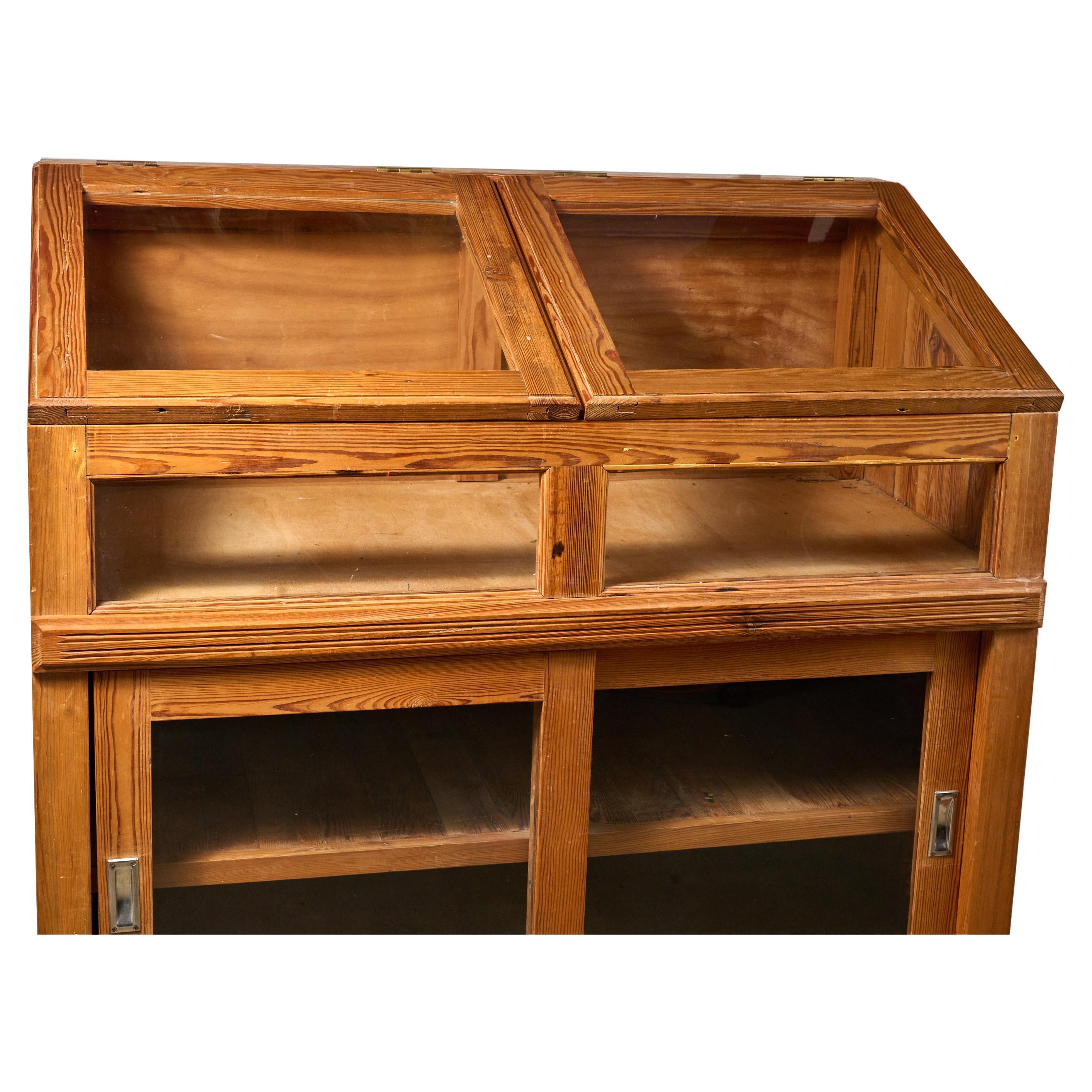 Argentine pitch pine and glass display case with plenty of storage. Quite useful. Great condition. Top glass doors flip up for easy access. 
