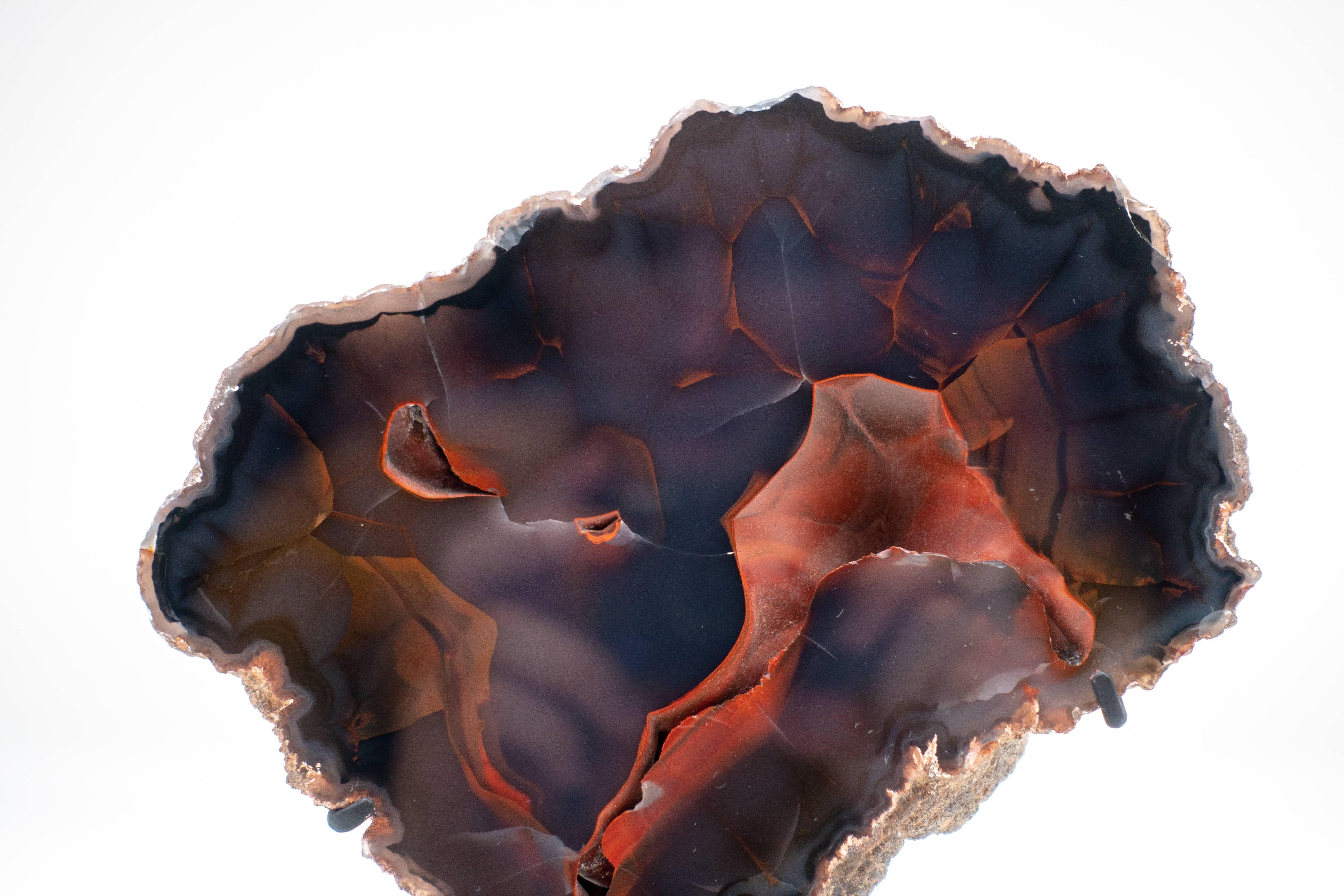 Argentinian Red Fox Agate specimen mounted on a black steel base. The smoky red-black Red Fox Agate is also known as Crater Agate, as these unique specimens are harvested close to an ancient crater near the town of Chubut, Patagonia, Argentina.