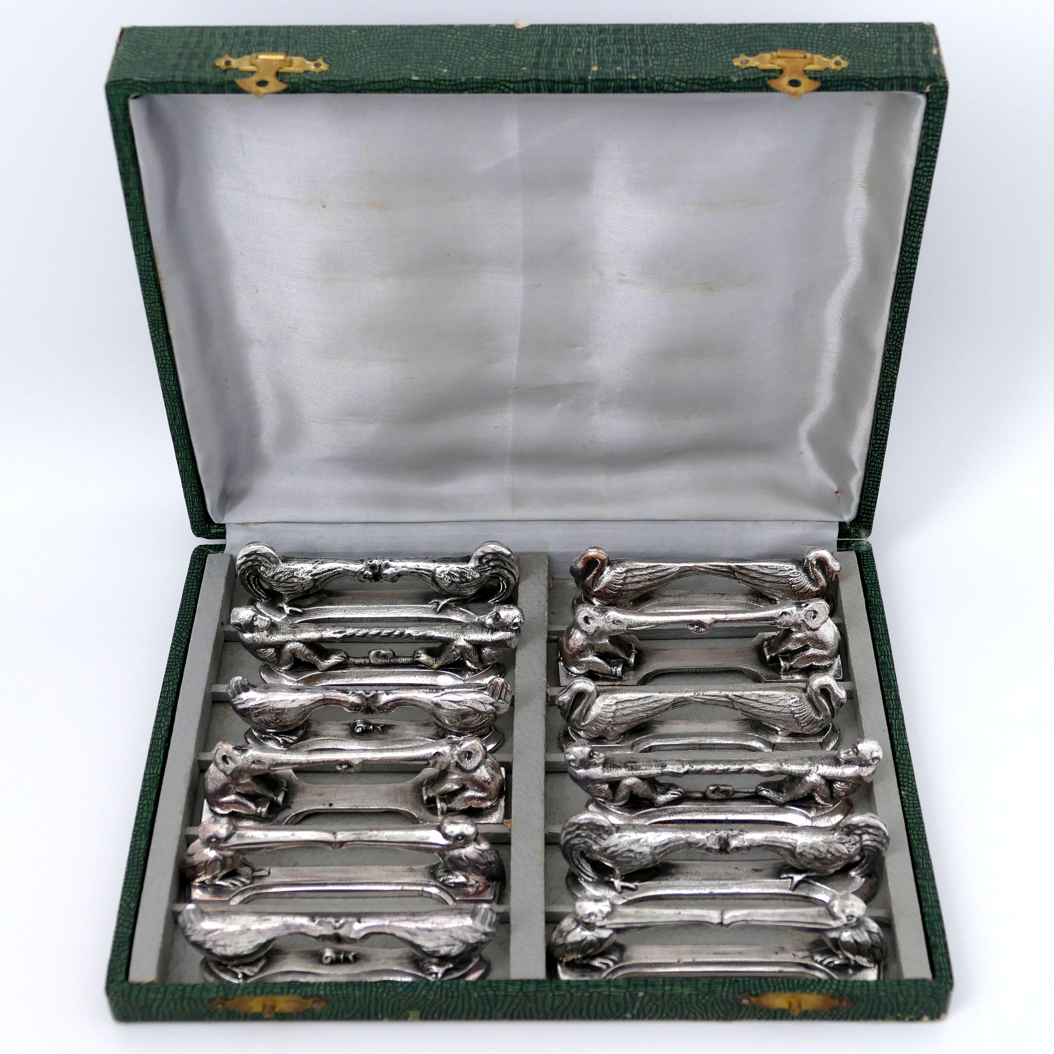 Rare set of twelve silver plate knife-rests in the shape of different animals: two swans standing turning their backs, two monkeys pulling a rope while standing by the tail, two cocks fighting each other, two hens clashing over a snail, two