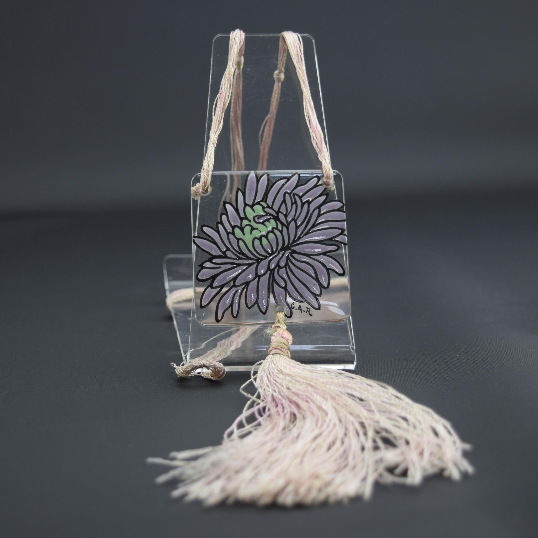 Argy Rousseau enameled chrysanthemum pendant C1920
Enameled in Lilac with a black outline and green center
Signed G.A.R for Gabriel Argy Rousseau
 Hung on a silk knotted cord and tassel 