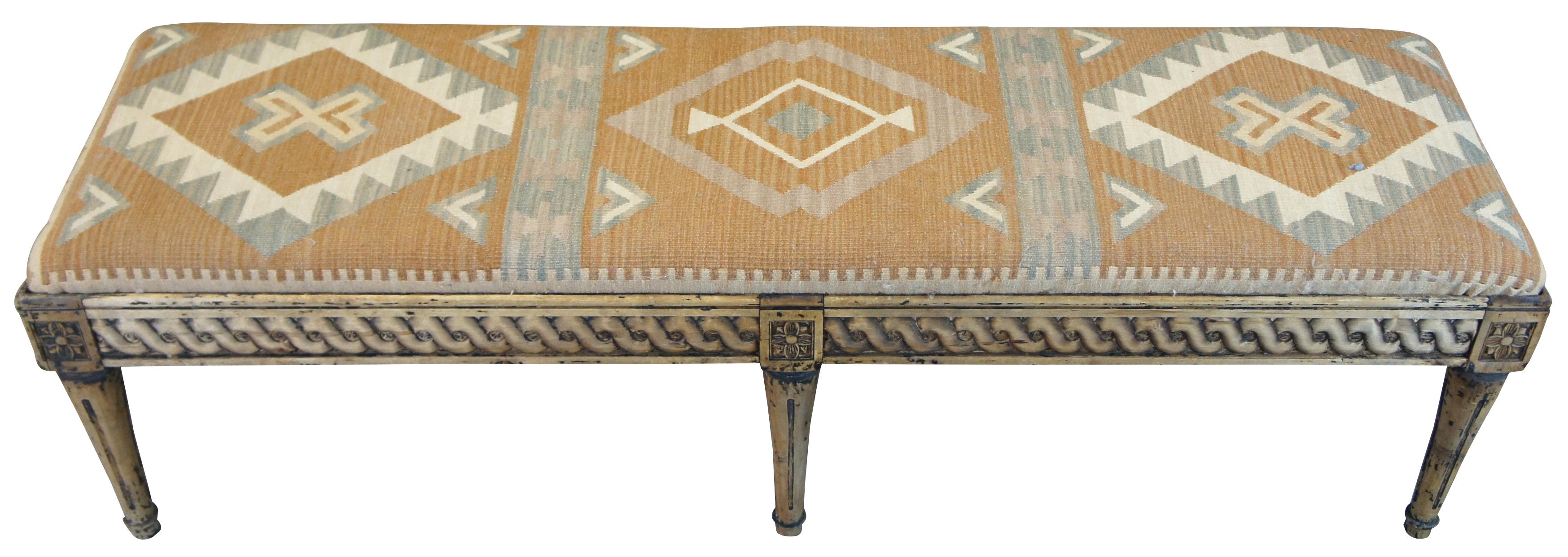Arhaus Furniture Louis XVI style bench. A rectangular form made from kiln dried naturally distressed hardwood. Features classic design elements including a helix carved apron flanked by floret medallions. The bench is upholstered in a southwestern