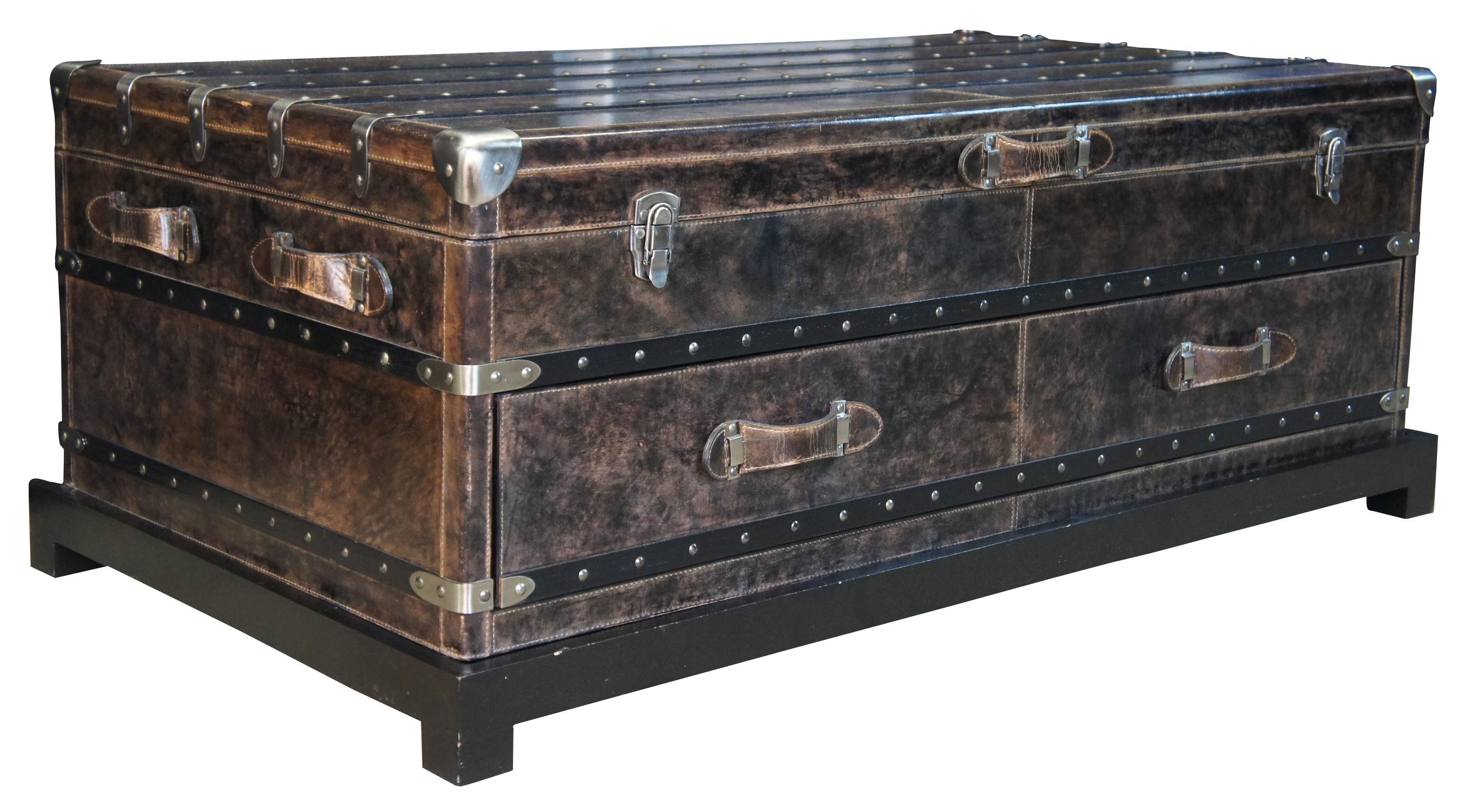 The Arhaus Martin coffee table is a stunning modern rendition of Victorian era steamer trunks. Beautiful brown leather with nickel riveted wooden trim. Includes one over sized drawer and a top compartment for accessory storage. Rests upon a