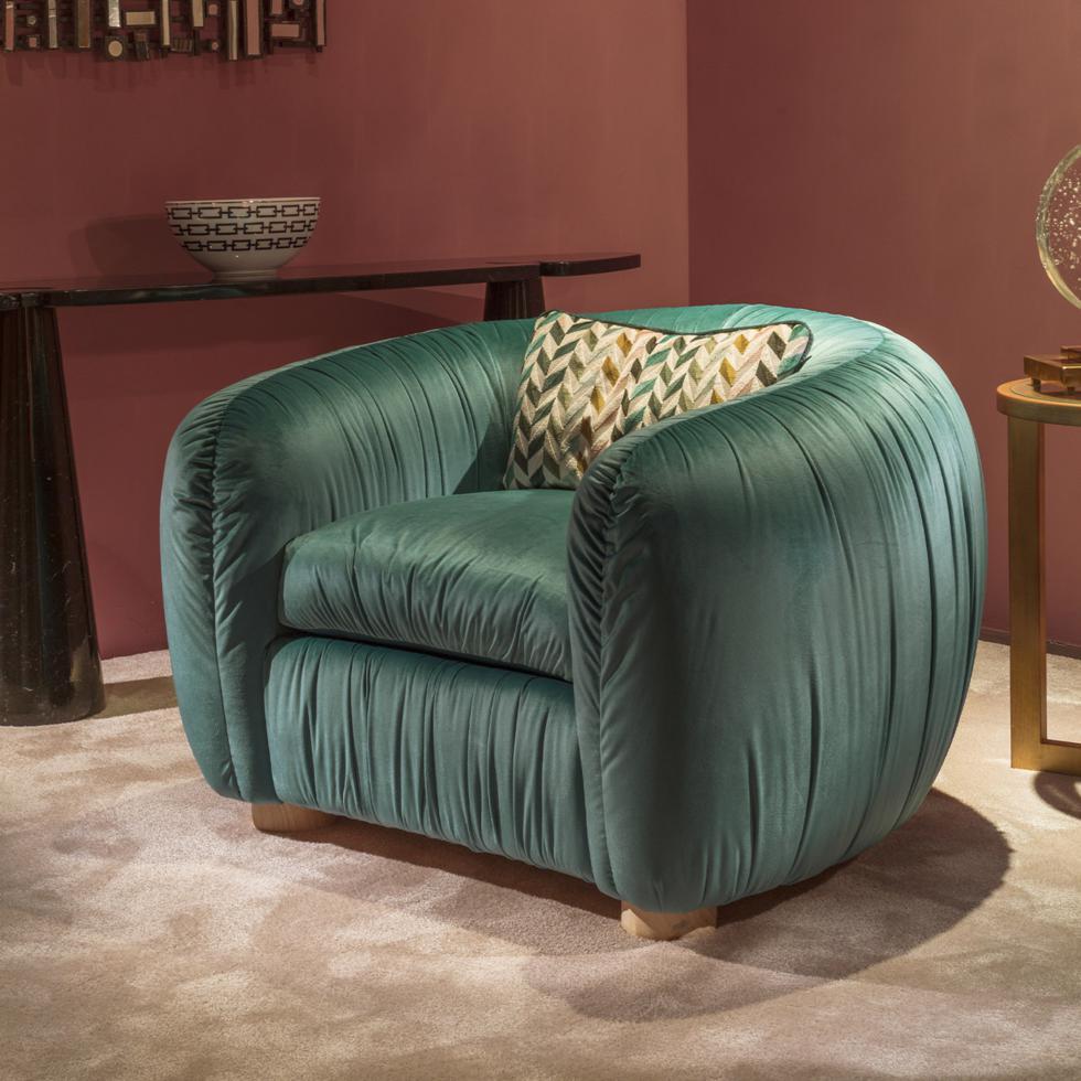 Marked by a distinctive Art Deco allure, this sumptuous Aria chair combines comfort and sophistication for refined classic or modern living interiors. One rectangular pillow is included. Showcasing a plushly padded barrel-shaped silhouette with