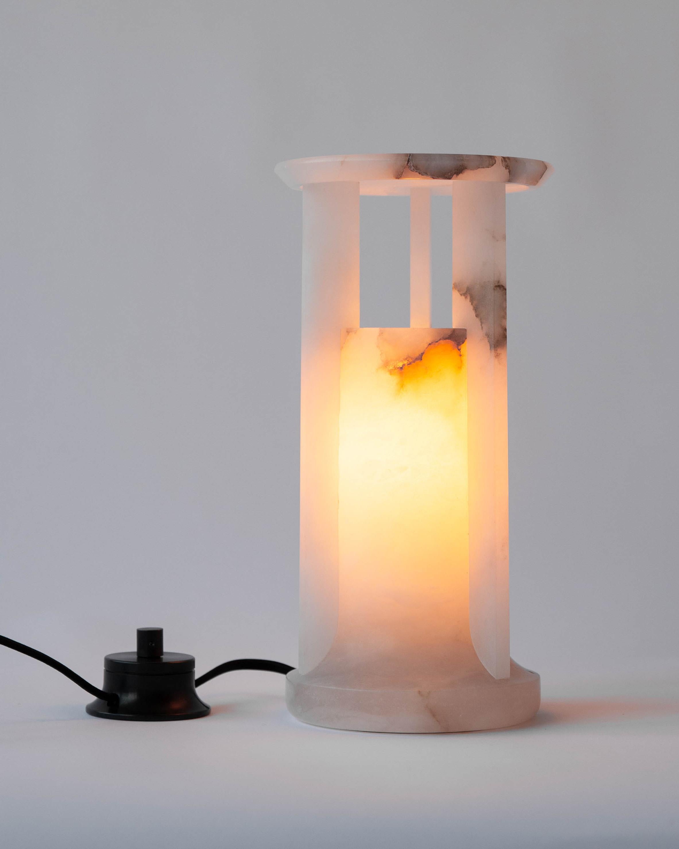 MTL4500
A hand-carved, veined white alabaster table lantern in a tempietto form with a pierced capital, supporting a broad top lens. Fitted with a heavy brass rotary dimming switch and an E12 LED lamp that emits a warm glow through the stone body.