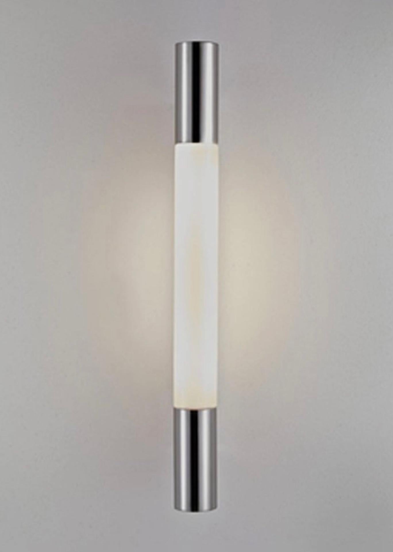 This sophisticated wall lamp is ideal for mirrors, staircases and hallways. It can only be mounted in an upright position with two matt stainless-steel cylinders at each end. Its special plastic diffuser ensures a very even distribution of light