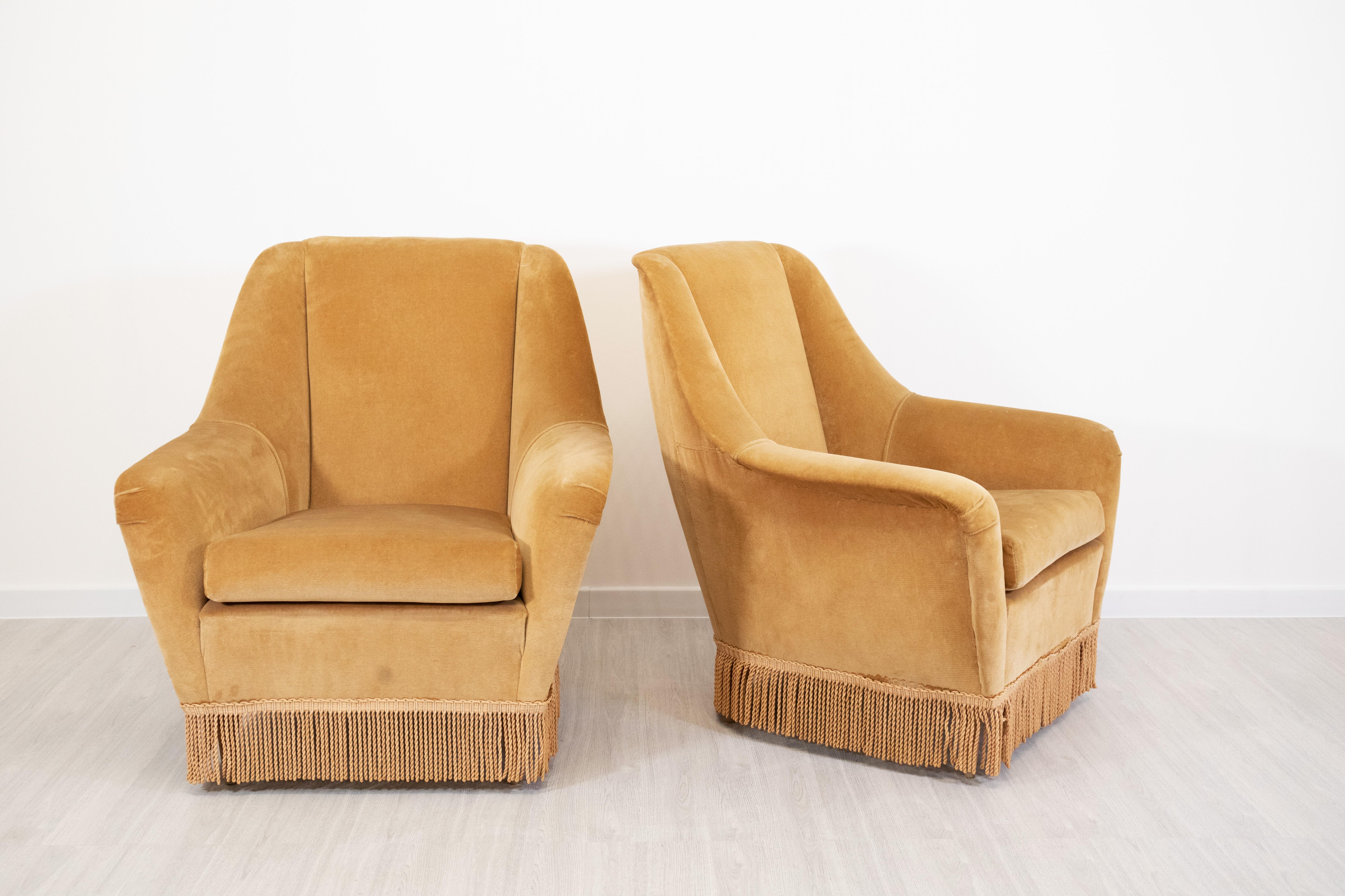 Élégante paire de fauteuils attribués à Ariberto Colombo, datant des années 1960, en provenance d'Italie. Ces pièces emblématiques sont dotées d'un cadre en bois massif et sont revêtues d'un tissu raffiné de couleur moutarde, avec des franges