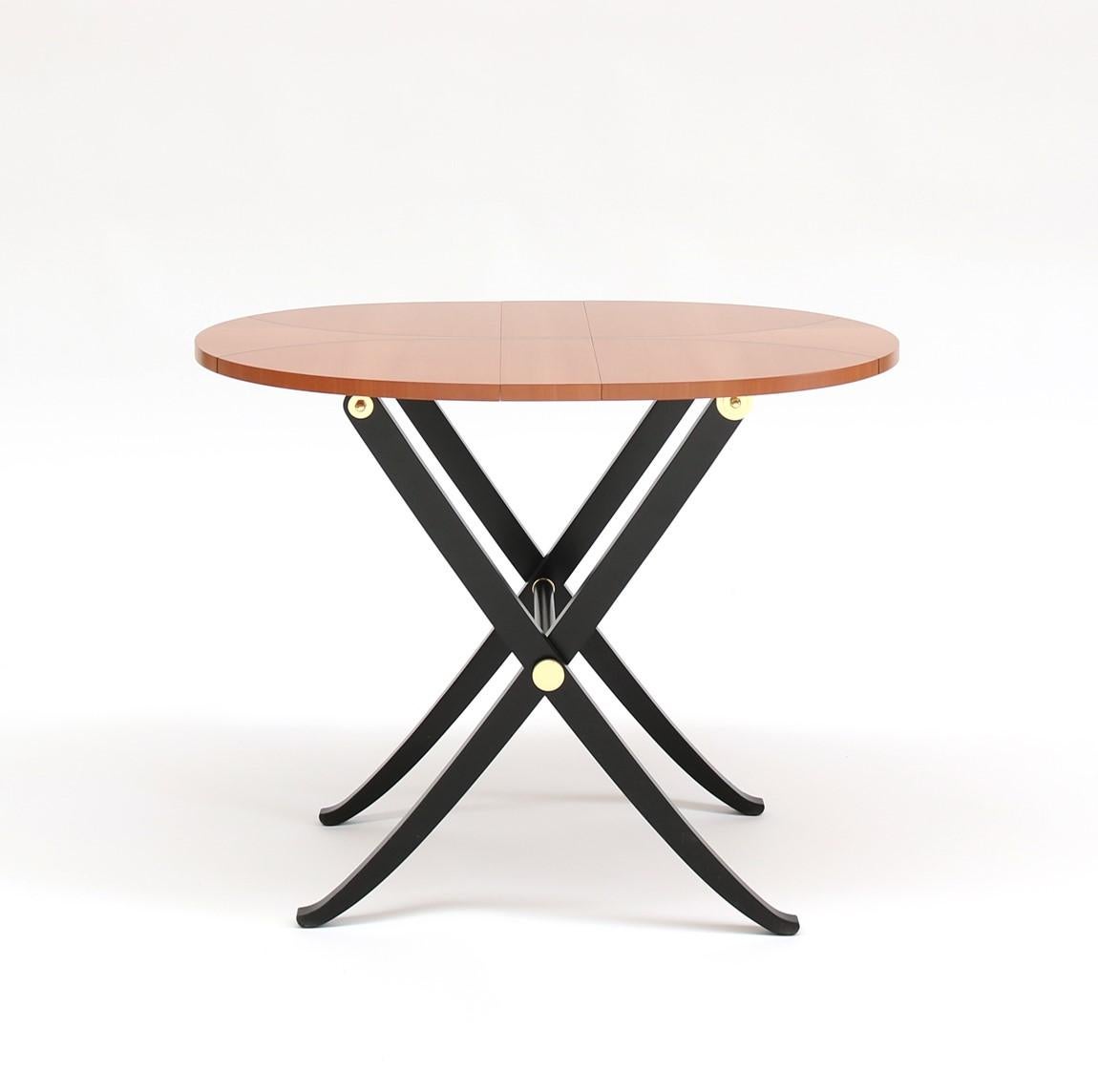 Foldable oval coffee table, made of pearwood. This wood has a delicate pinkish color that contrasts with the black lacquer of the legs. The top is divided into three parts to allow the folding and it is decorated with an ebony inlay drawing a curved