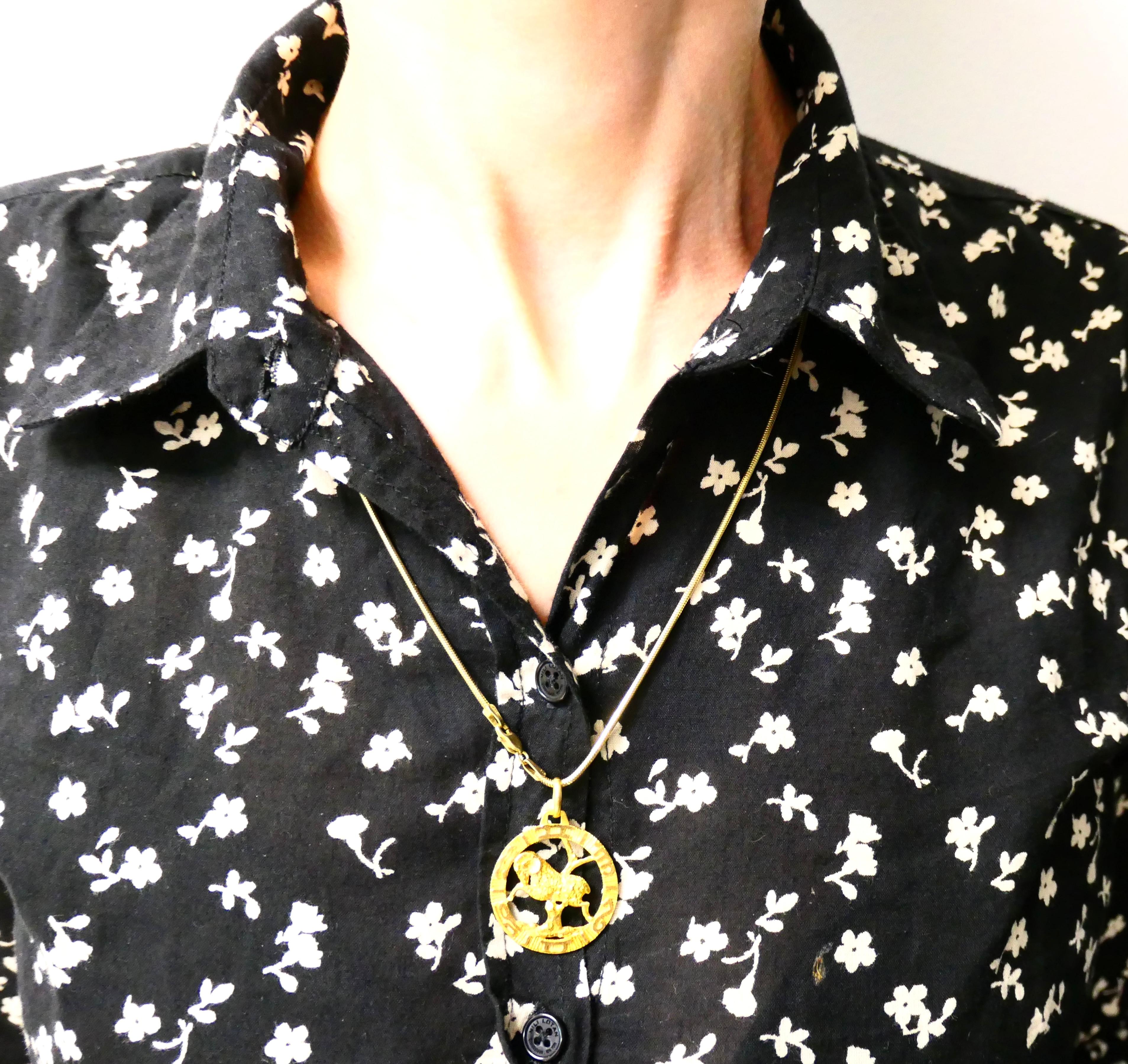 Pendentif en forme d'Aris, réalisé en or 18 carats, avec un collier à chaîne serpent en or 14 carats.
Le pendentif est ajouré ; il présente un bélier détaillé, symbole classique de l'Aris, serti à l'intérieur d'une
cadre circulaire texturé. Les