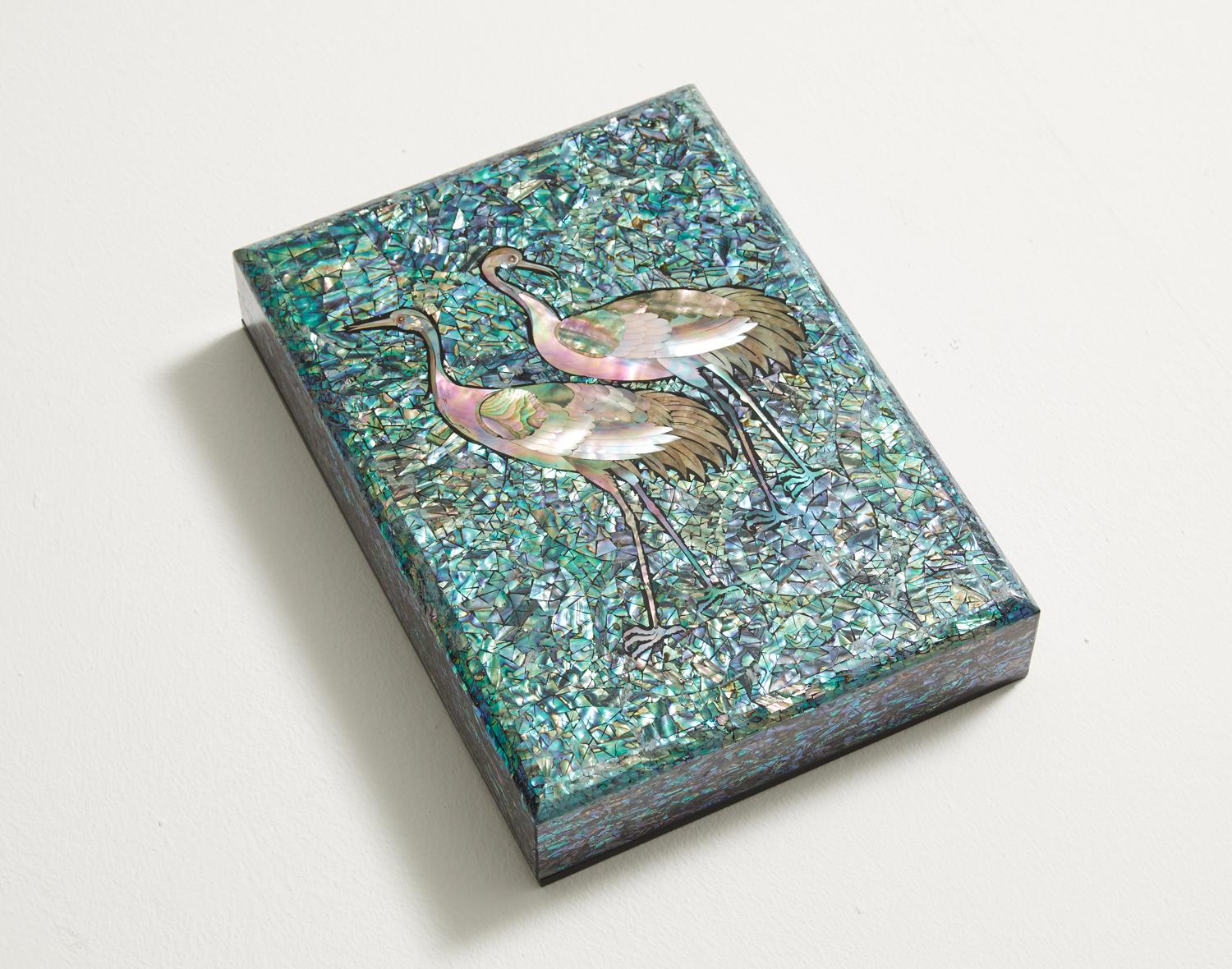 This artwork presents a wooden box inlaid with the image of cranes carved from mother of pearl. The sky is engraved with the blue shade of mother of pearl to highlight the profound mysteriousness of the cranes. The brilliant light shines gloriously