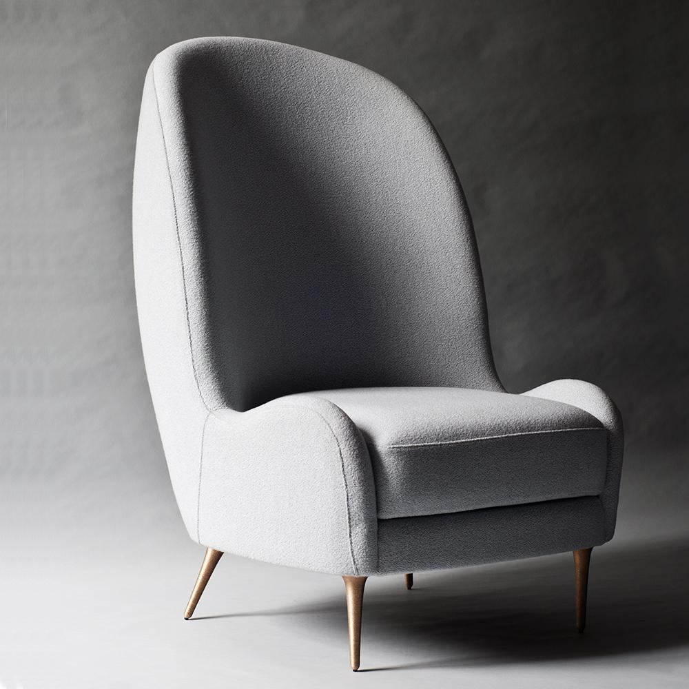 The Aril side chair by DeMuro Das features a curved, elongated tight back and loose seat cushion. The hand-cast solid bronze legs are finely detailed with horizontal grooves. Construction includes solid hardwood frame with European webbing and