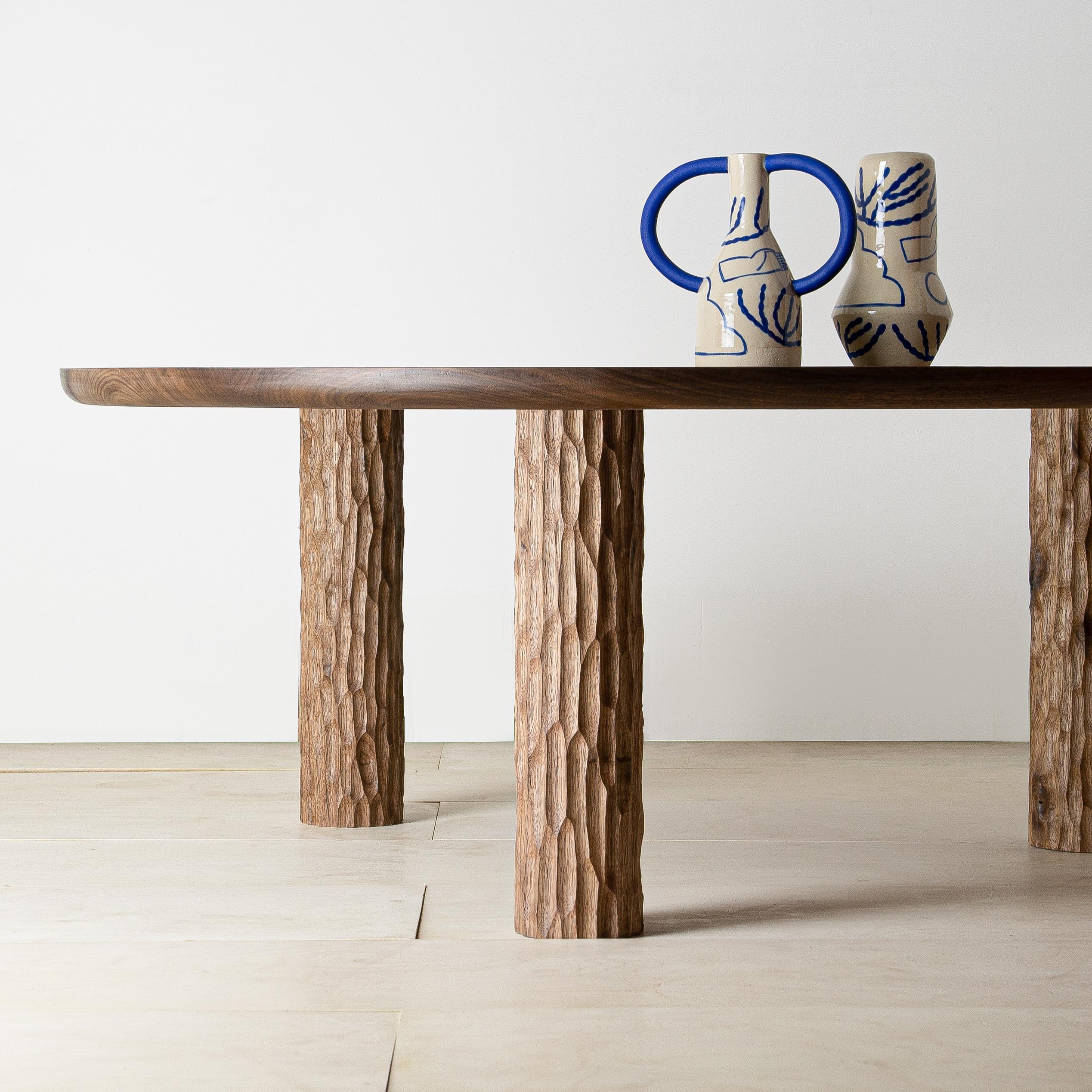 This striking yet pared back design is crafted from solid English walnut. Presenting contrasting textures, a generously-sized round tabletop sits atop three textured, hand-carved cylinders. Utilising traditional joinery, the two elements are joined