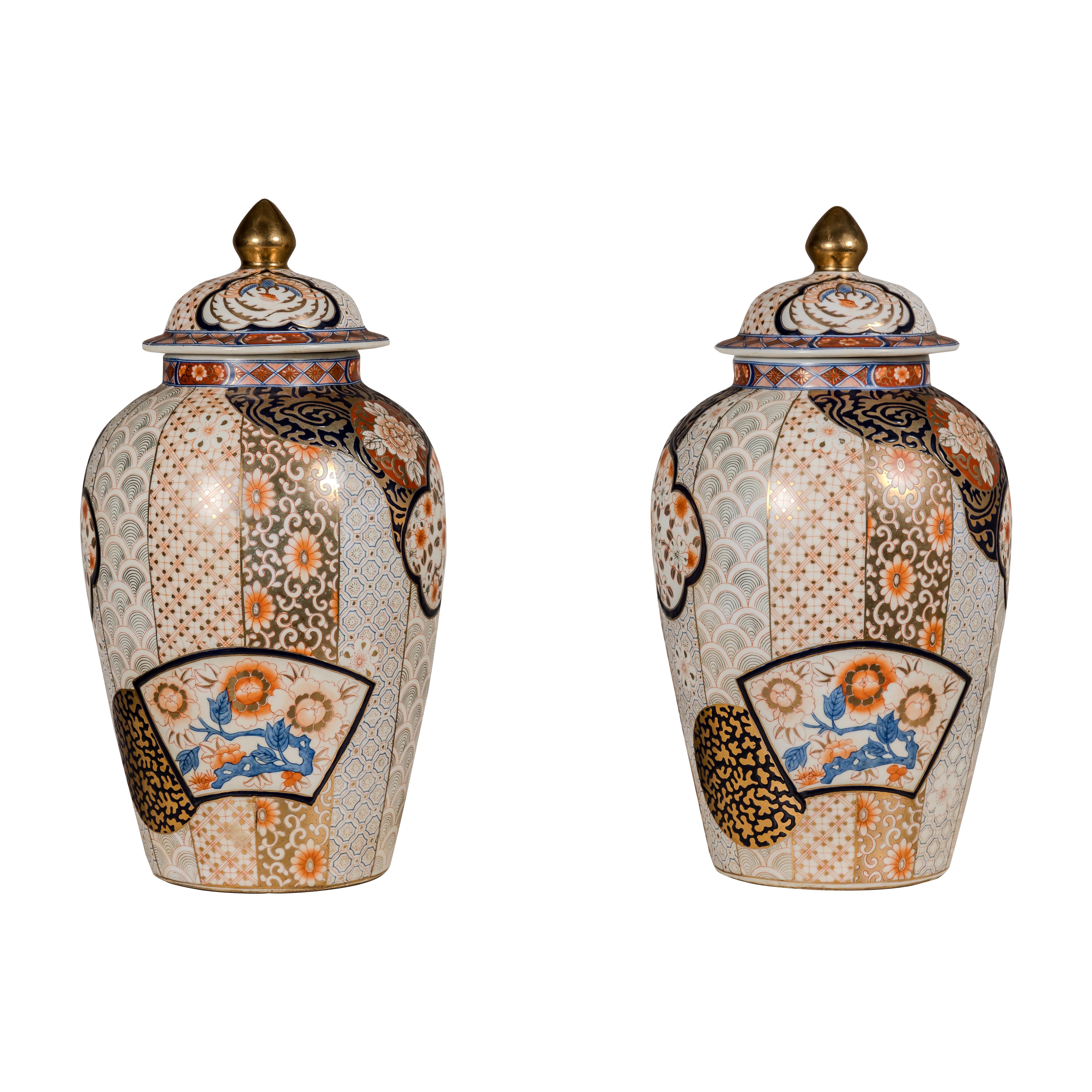 A pair of vintage Arita Japanese style lidded jars with gold, blue and orange floral motifs. This pair of vintage Arita Japanese style lidded jars is a splendid example of the fine craftsmanship and aesthetic beauty characteristic of traditional