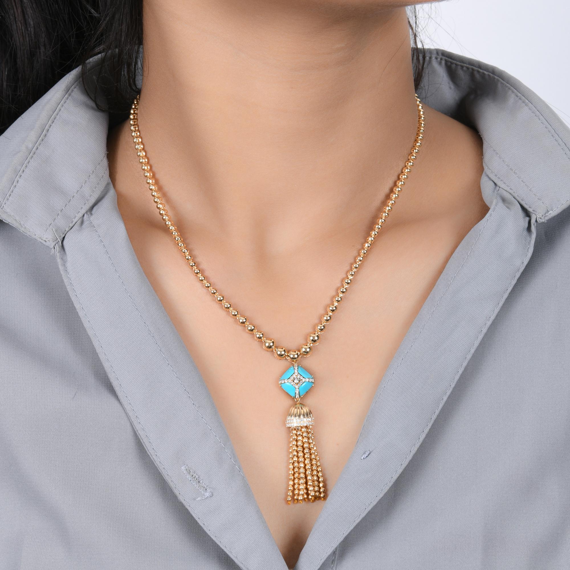 Ce collier à pompon en or jaune 18 carats et turquoise d'Arizona se compose d'une chaîne en perles d'or au niveau du décolleté, d'un coussin turquoise serti de diamants et de perles d'or qui pendent en guise de pompon.
La turquoise symbolise la