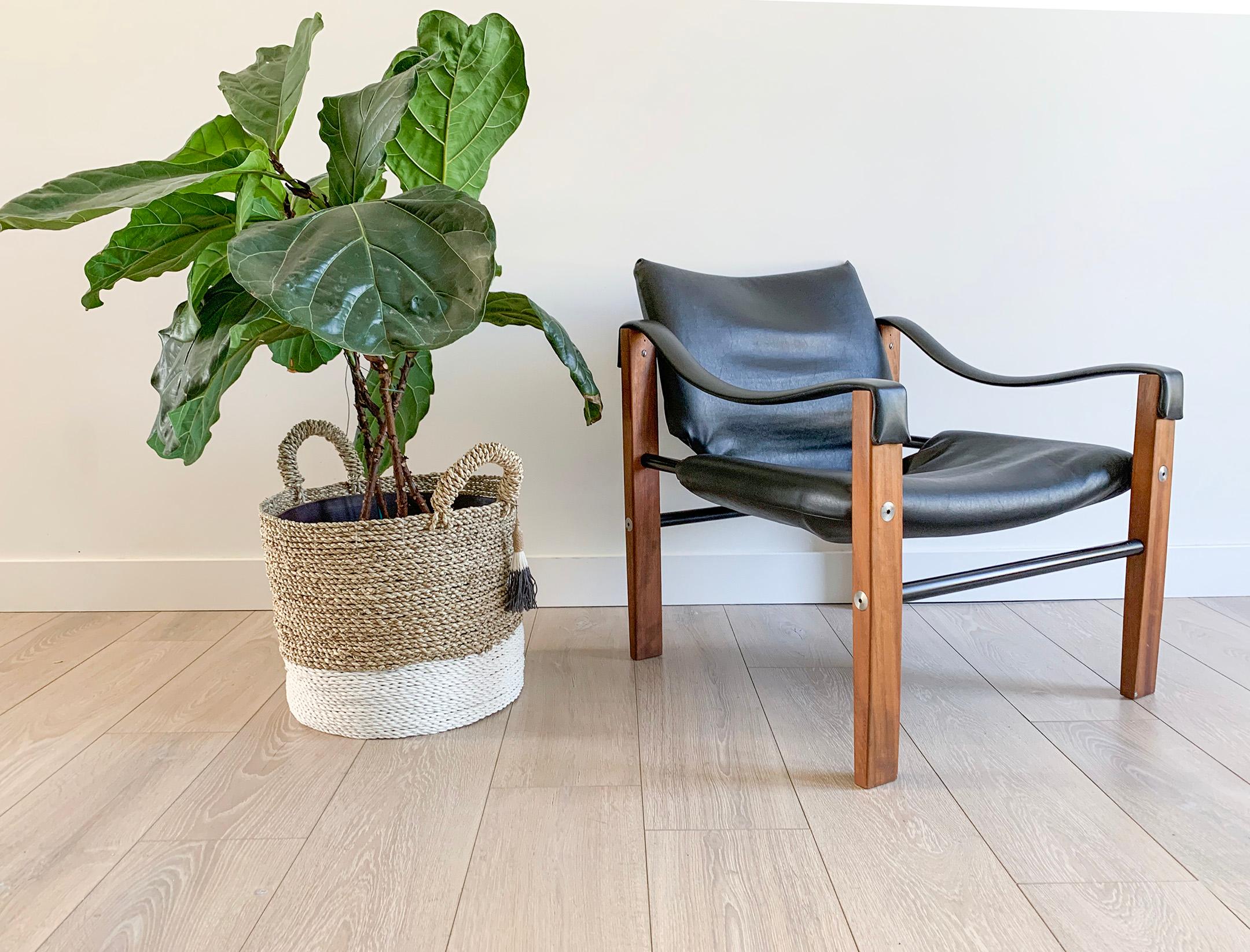 Available right now we have this stunning safari chair designed by Maurice Burke in Bath England, 1970s. This black safari chair is upholstered in a black marine grade vegan leather and is accented with stainless steel rivets on a gorgeous teak