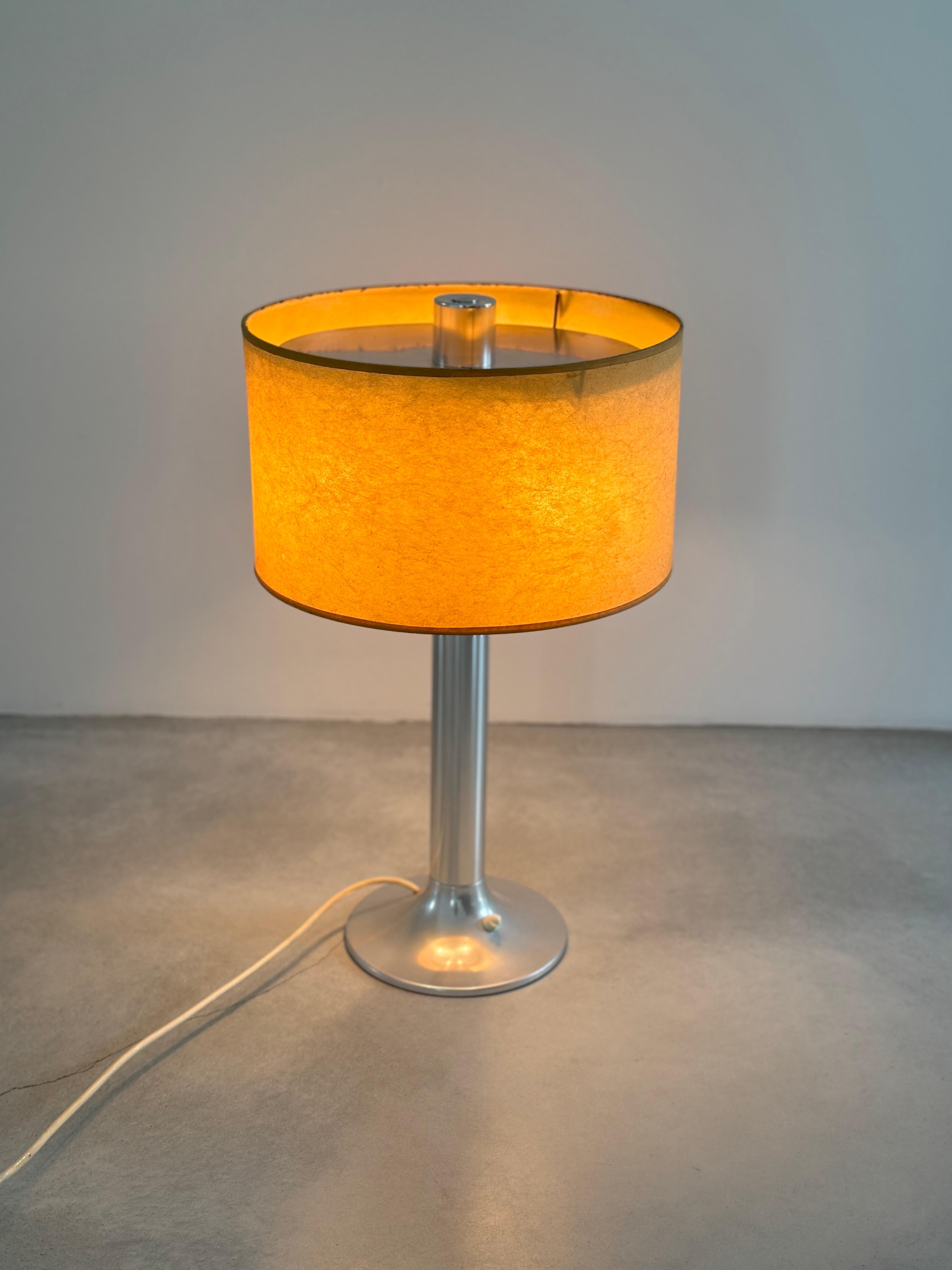 Schöne Schreibtischlampe mit futuristischem und klassischem Design.

Zylindrischer, ausgestellter Sockel aus gebürstetem Aluminium, Lampenschirm aus Leinen.
Ausgabe ARLUS DIFFUSION.

Die Lampe ist in gutem Zustand, einige Gebrauchsspuren, der