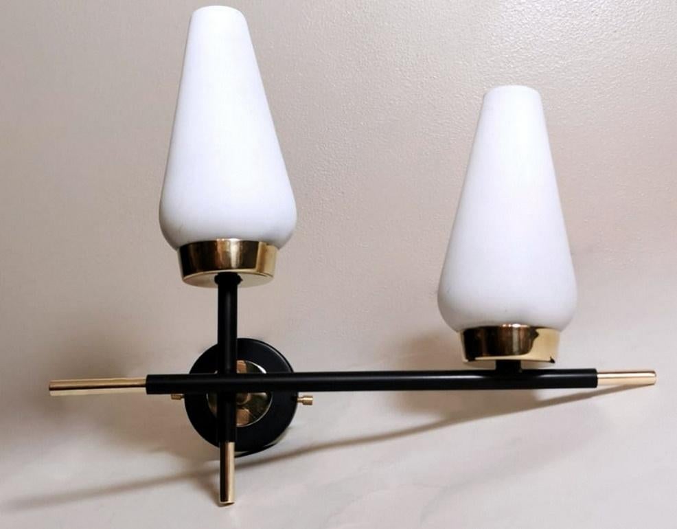 Elegant and linear wall sconce; the original and solid structure is made of brushed and polished brass; a part has been fire painted in black creating a pleasant contrast; the design is compact and functional; the asymmetric and innovative