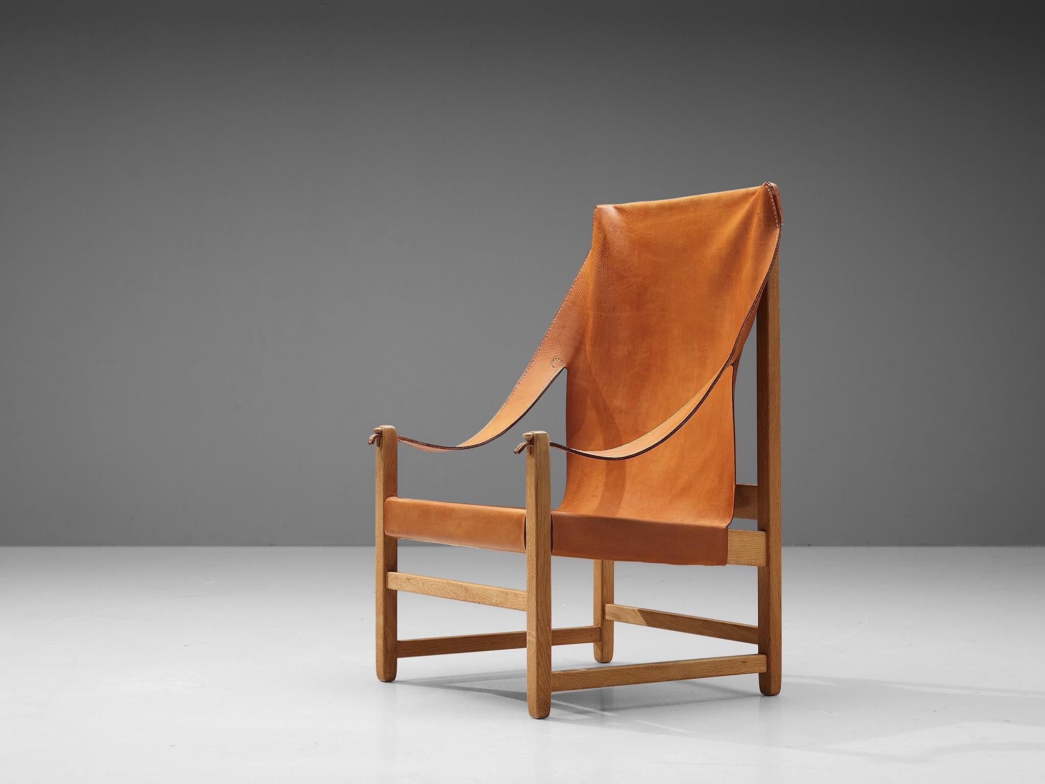 Grand armchair, oak and leather, Netherlands, 1960s.

Wonderful armchair with a majestically high back in solid oak and cognac saddle leather. The leather seats, back and armrests have aged in a wonderful way, and emphasize the strong character of