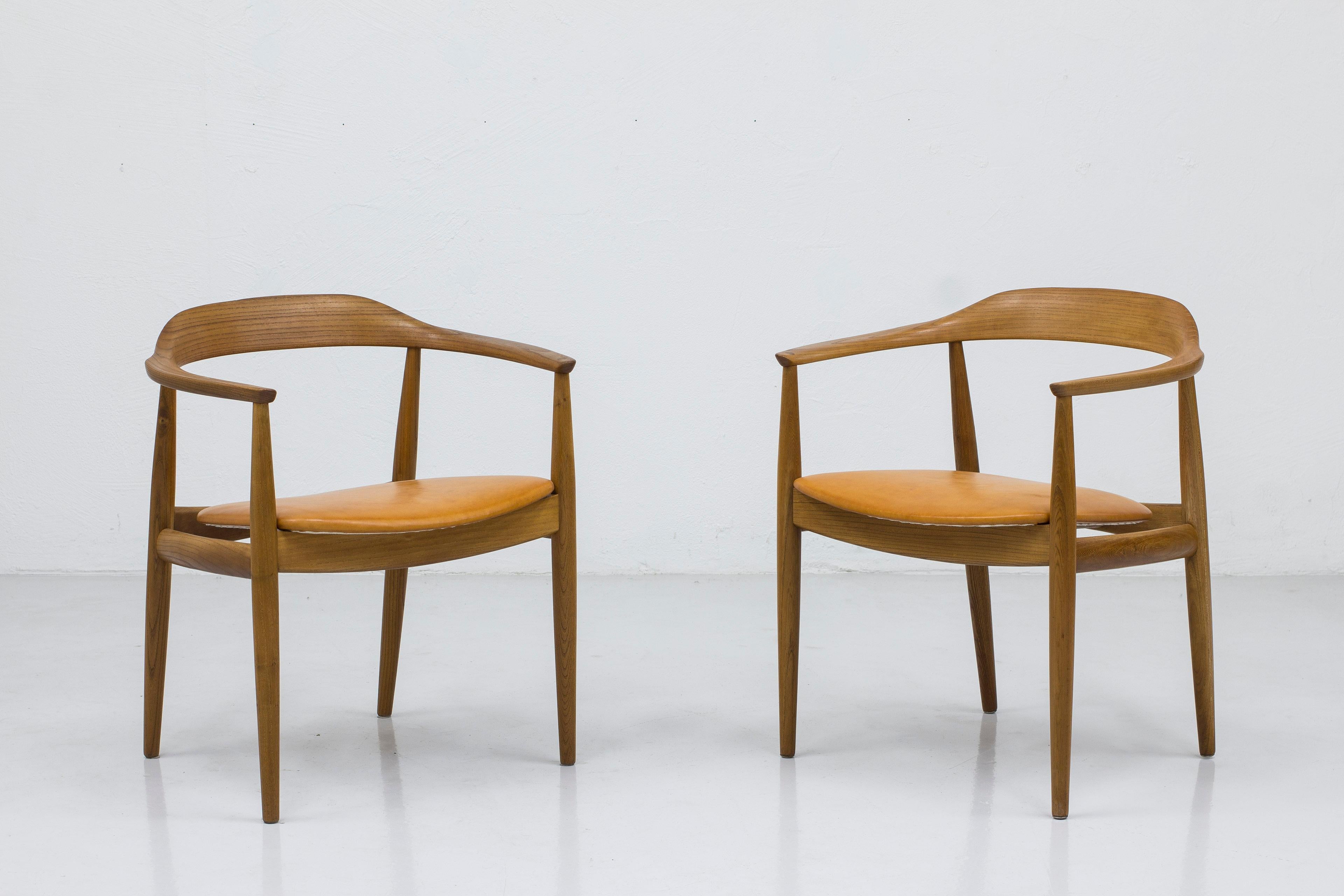 Arm chairs designed by Arne Wahl Iversen. Manufactured in Denmark by cabinet maker Niels Eilersen during the 1950s. Made from solid elm with beautiful grain and structure and seats with cognac leather. Very good vintage condition with few signs of