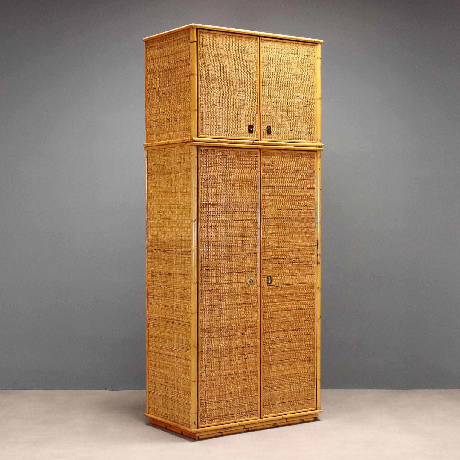 Armadio vintage realizzato in bambù e vimini a due ante composto da una base con appendiabiti e cassetti, alzata con ripiano. Maniglie in ottone.